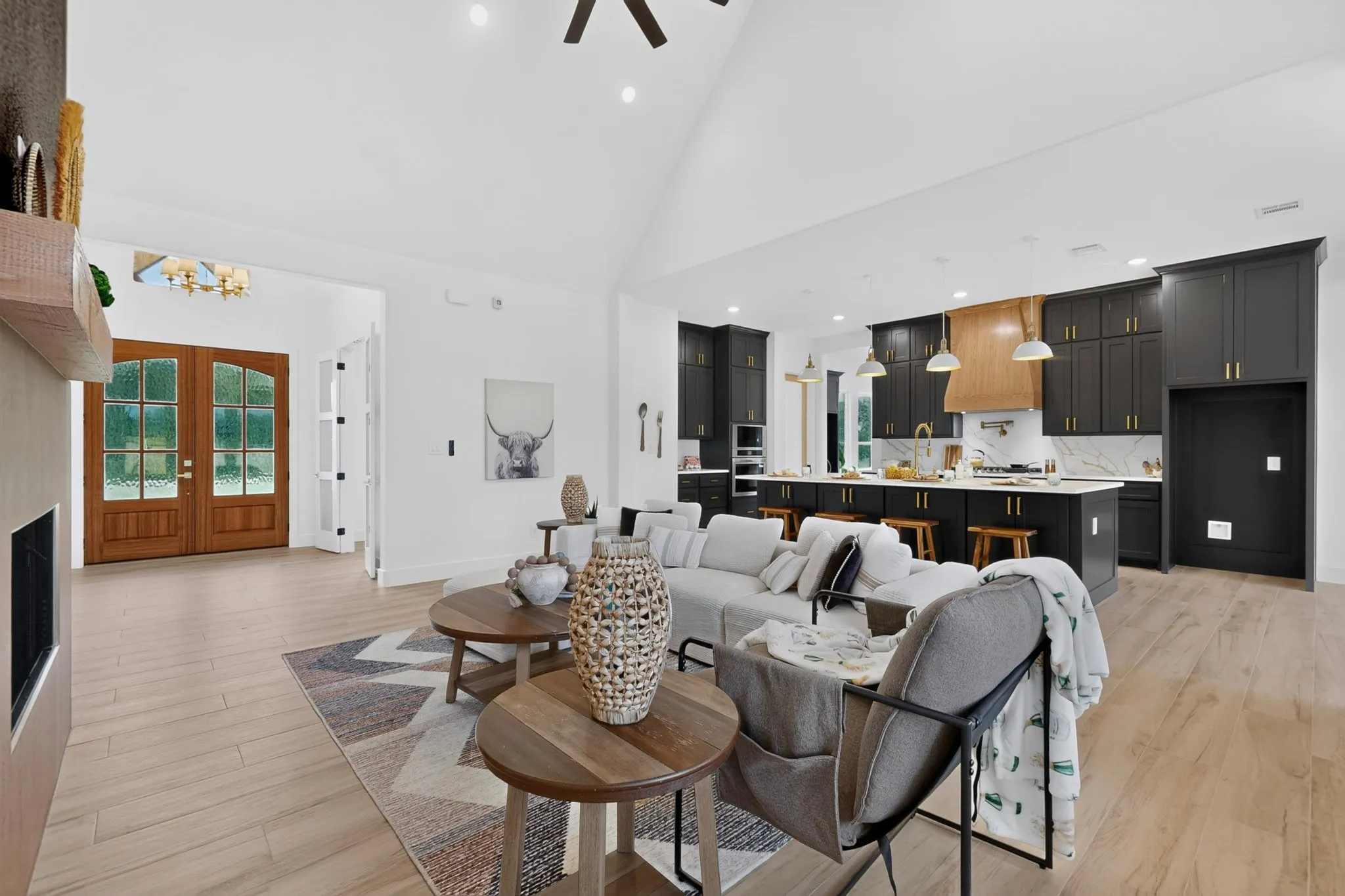 Vaulted ceiling design with recessed lighting, wood-finish flooring, and a contemporary fireplace with a wood mantle