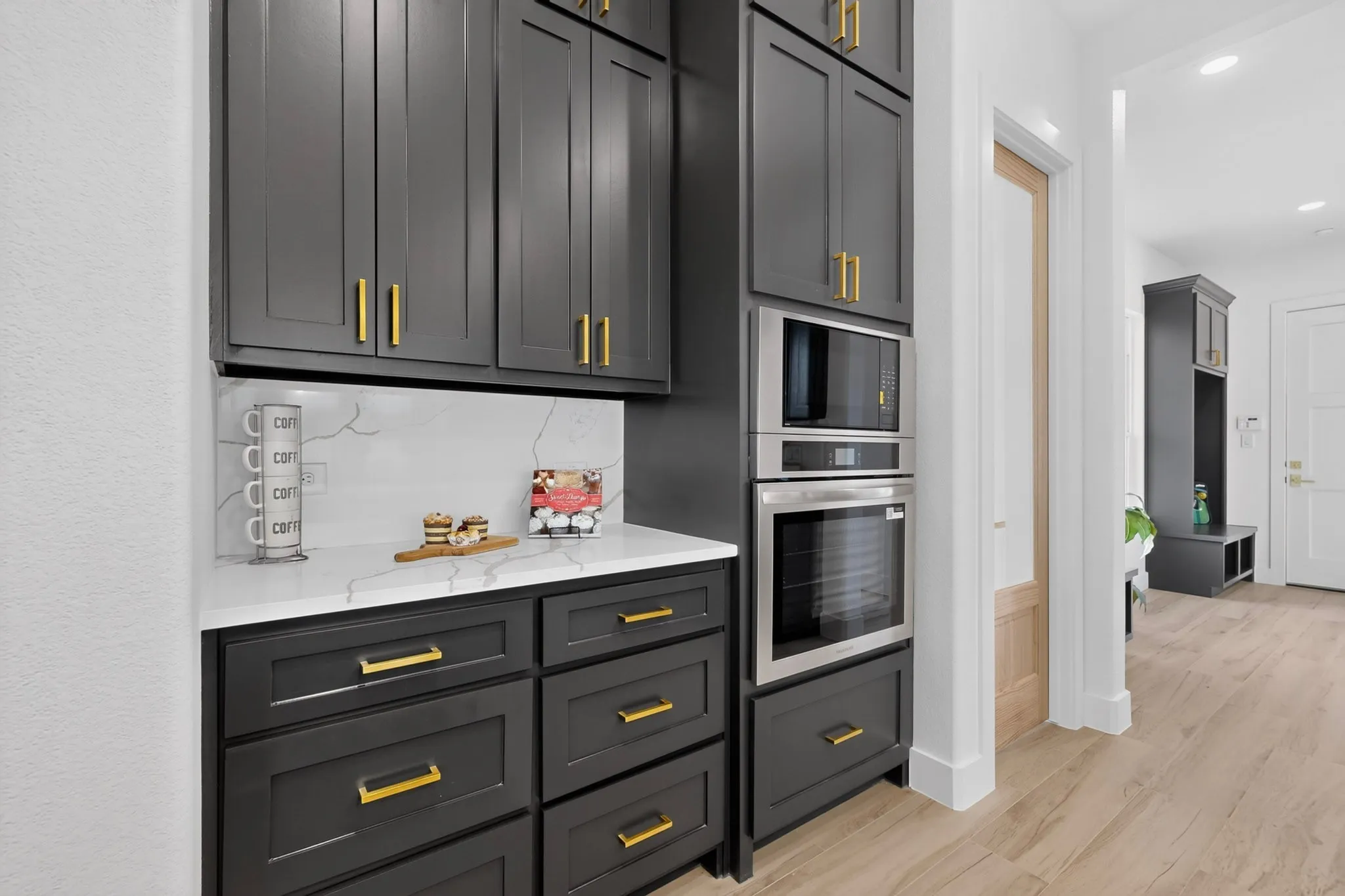 Built-in stainless steel microwave and oven, set within dark cabinetry featuring gold-tone hardware