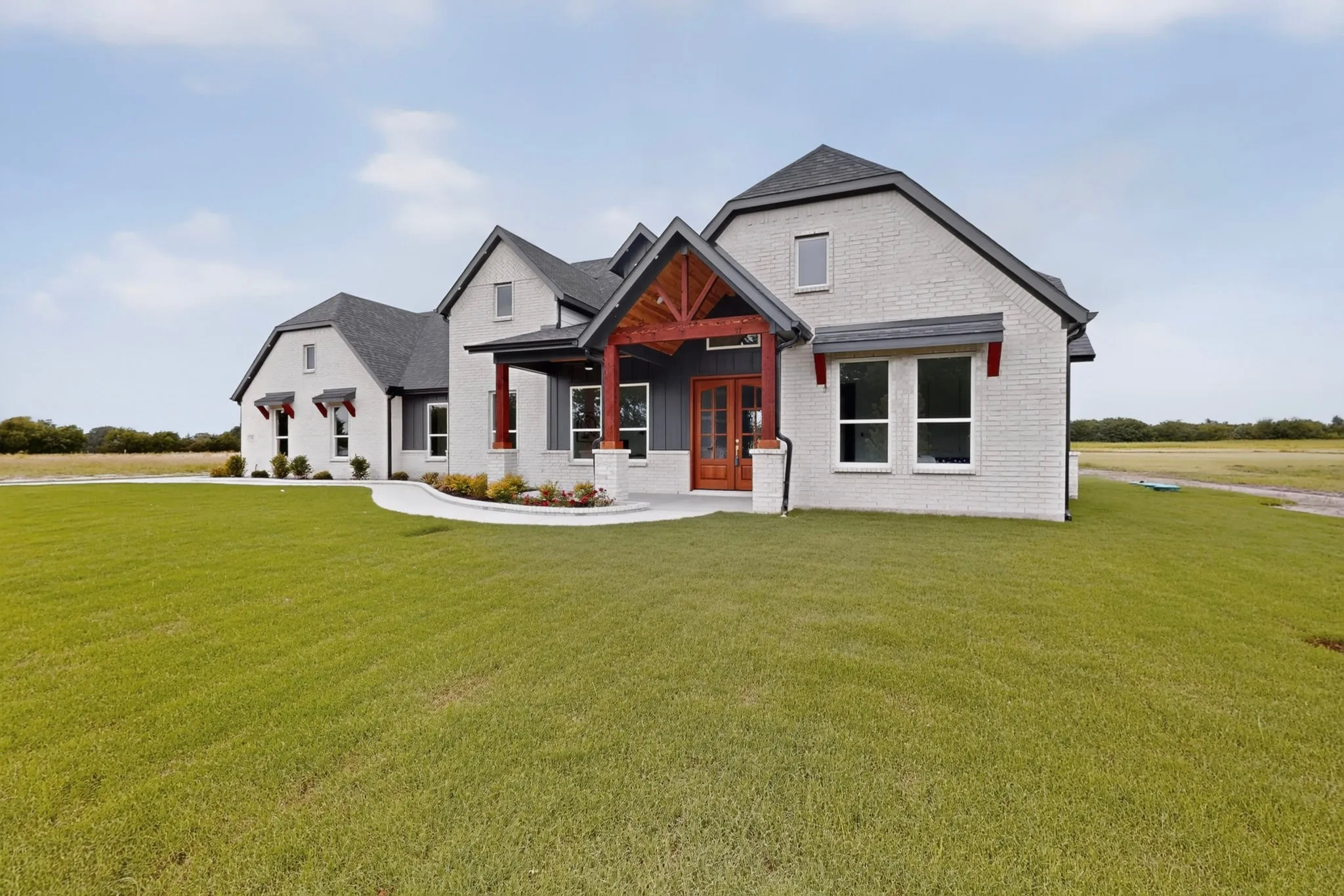 Contemporary farmhouse exterior featuring light brick, dark gray gables, dark wood-tone porch beams, and a wood-paneled double entry door
