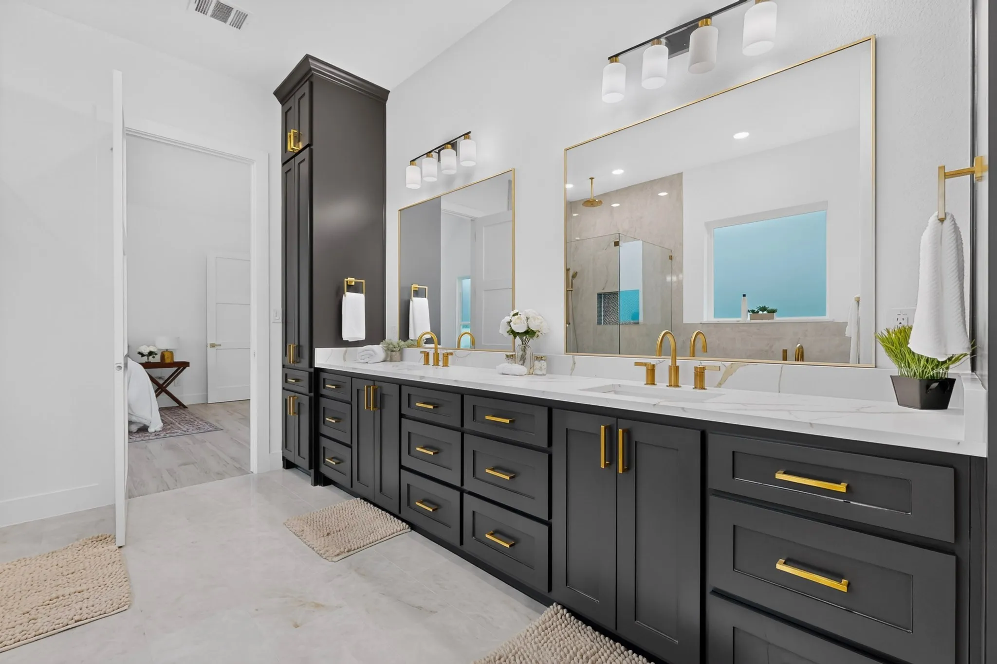 Spacious bathroom featuring a dual vanity with dark cabinetry, gold hardware, and white countertops