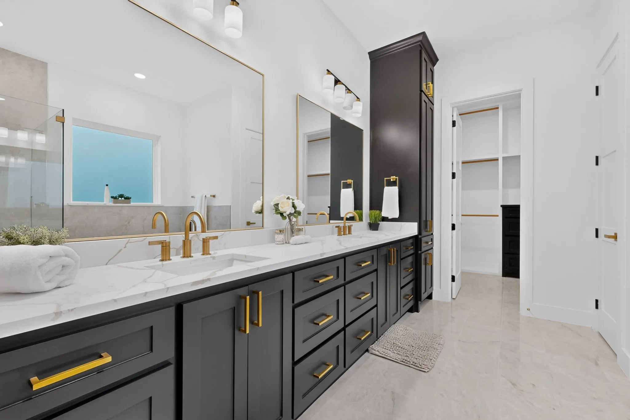 Double vanity featuring dark cabinetry, gold-toned hardware, and a white countertop with integrated sinks