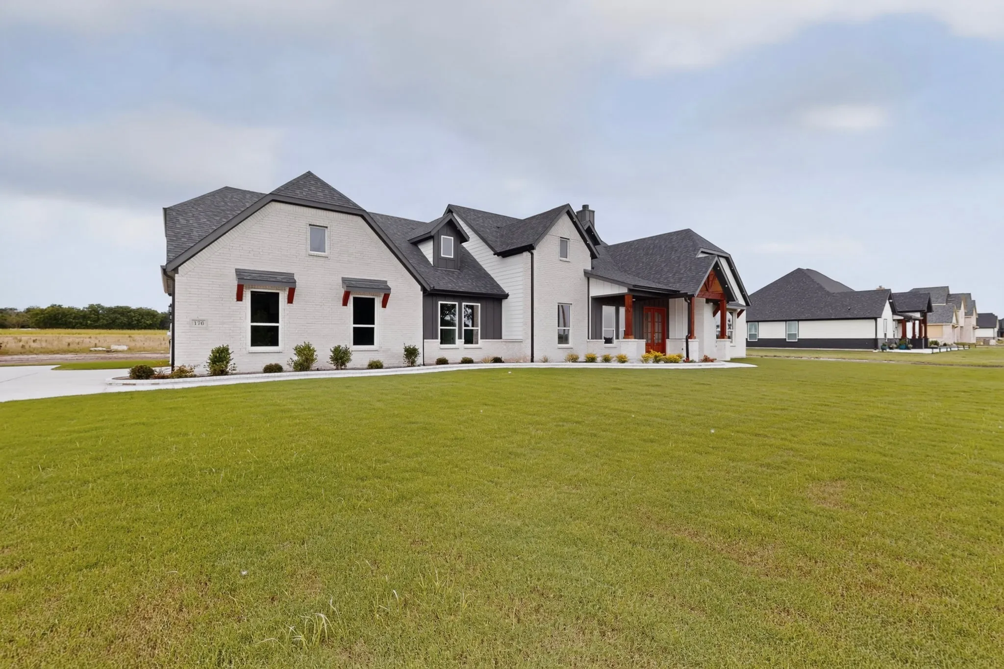 Contemporary farmhouse architecture with a light brick facade and dark gray siding accents