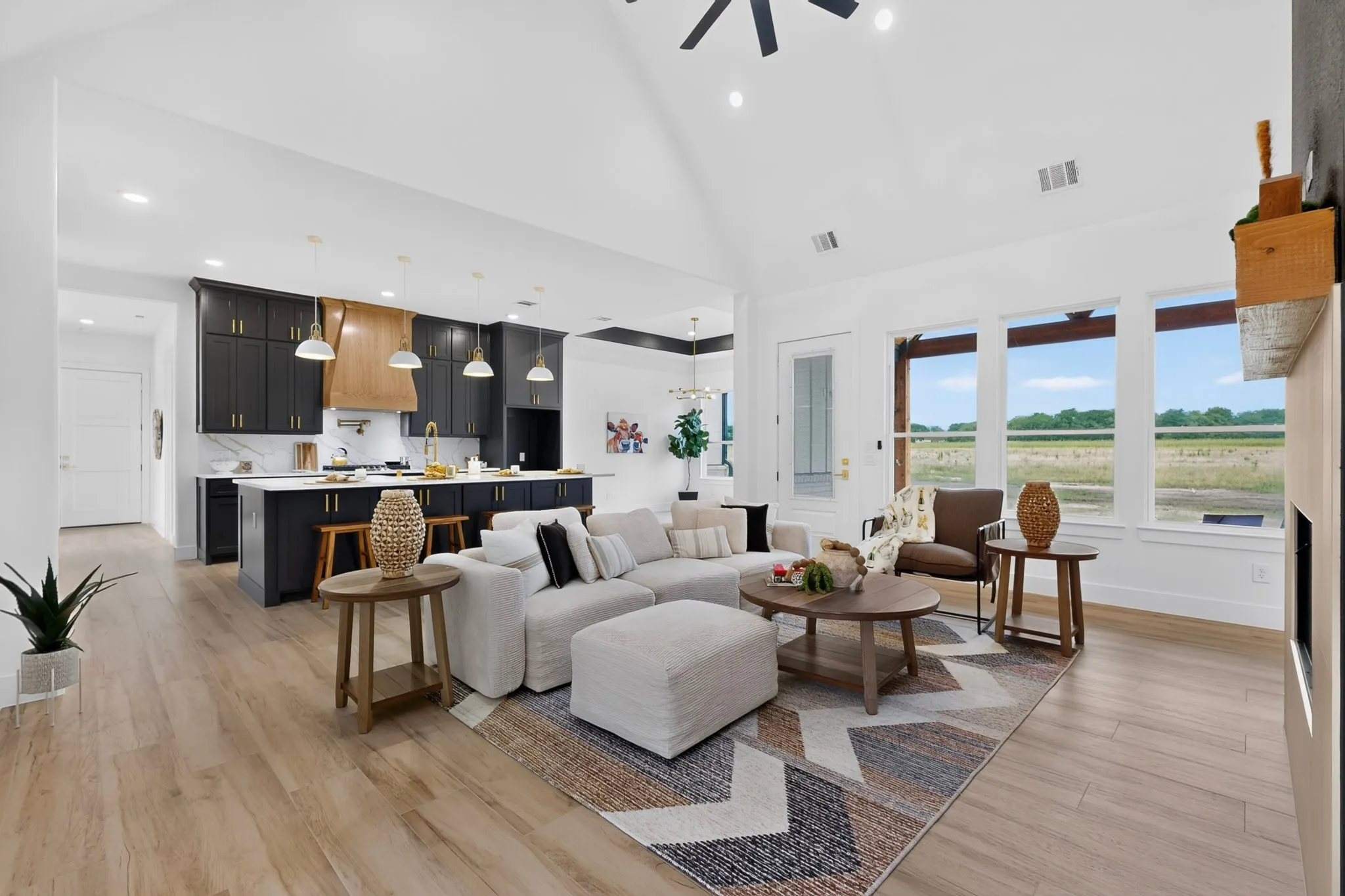 Open-concept living space featuring wood-finish flooring, vaulted ceilings, and large windows