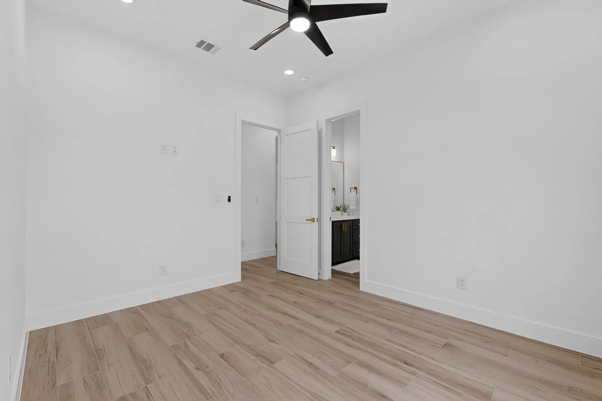 Spacious room with wood-finish flooring, recessed lighting, and a contemporary ceiling fan