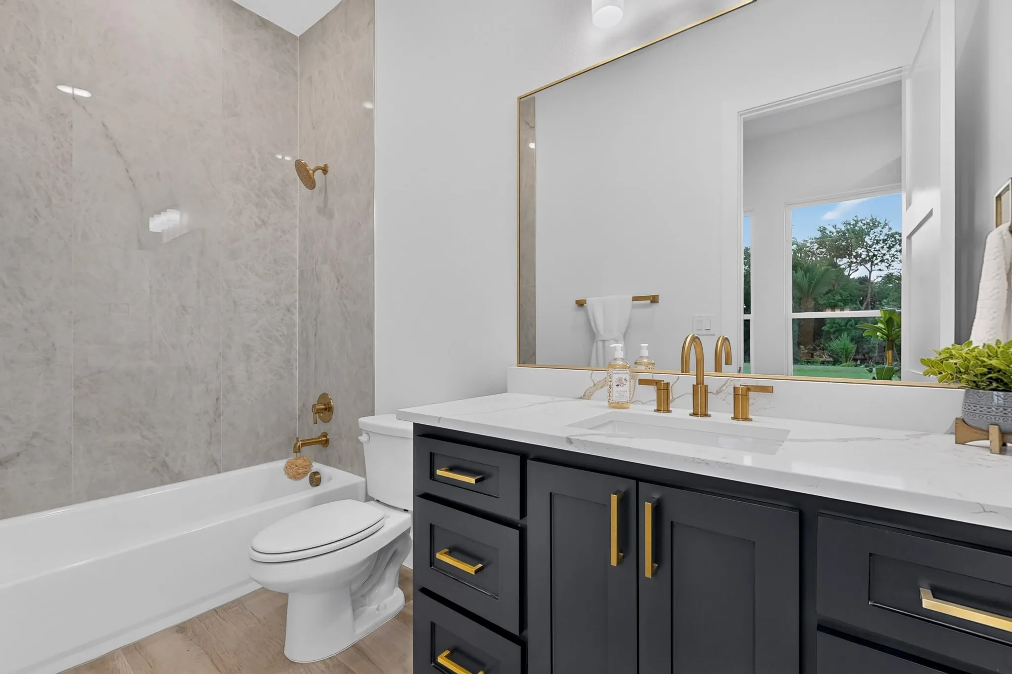 Bathroom featuring a dark vanity with gold hardware, white countertop, and gold-finish fixtures
