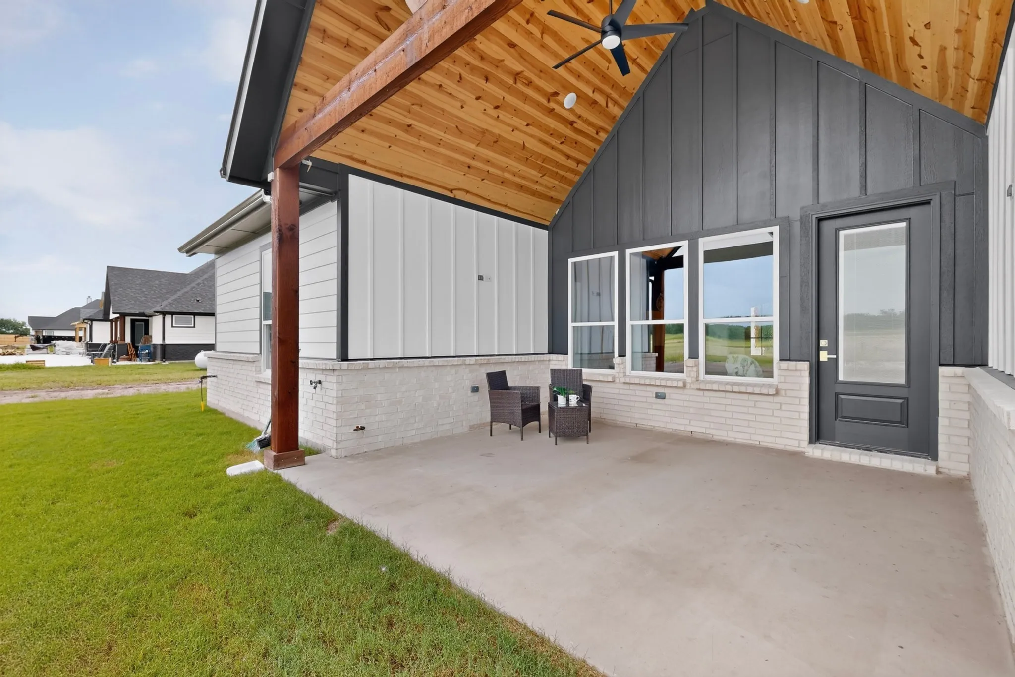 Covered outdoor patio featuring a vaulted wood-finish ceiling, exposed wood beams, and a ceiling fan