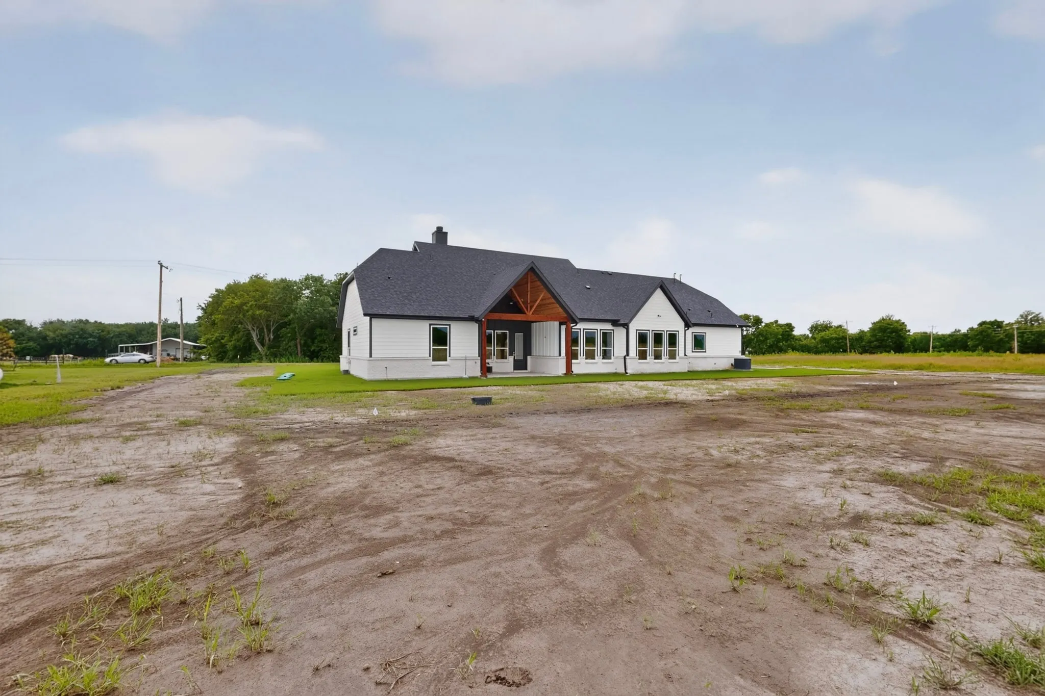 Contemporary ranch-style residence featuring a dark shingle roof, white siding, and a prominent wood-clad entryway