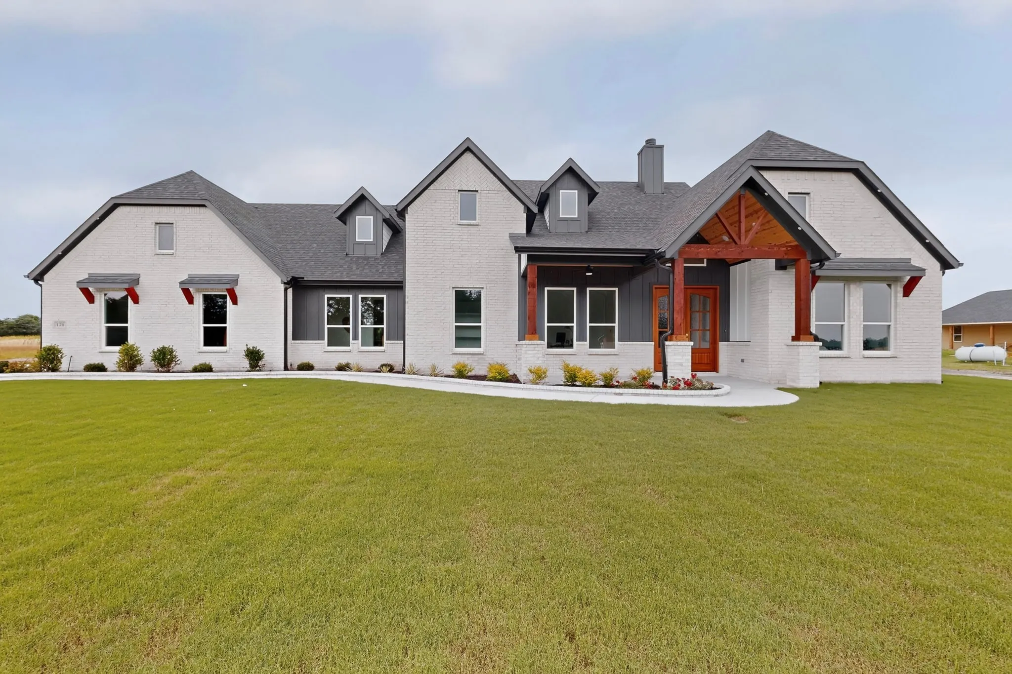 White brick exterior featuring dark gray trim and a prominent wooden beam entryway