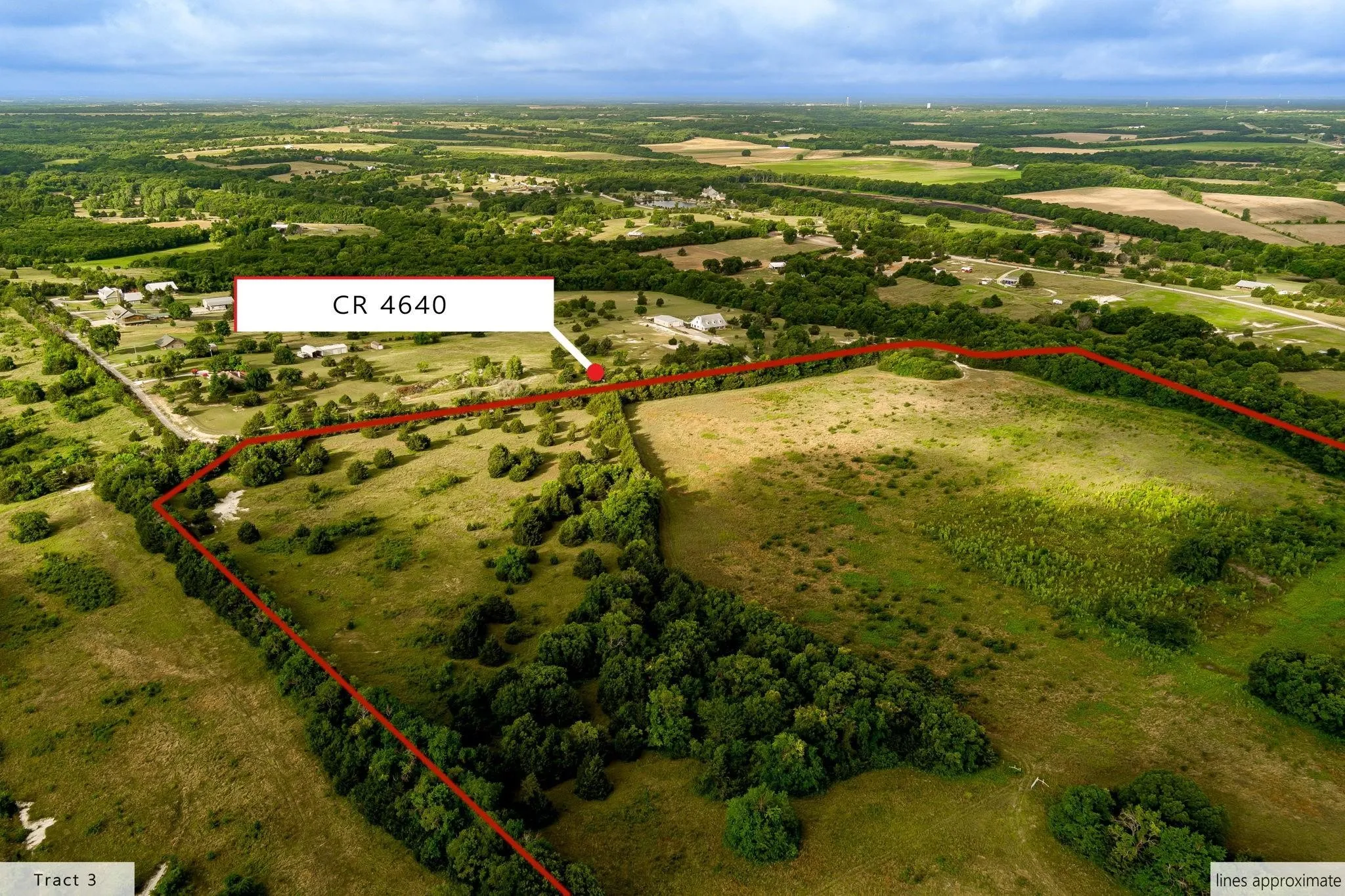 Expansive rural landscape featuring a mix of open fields and mature tree lines