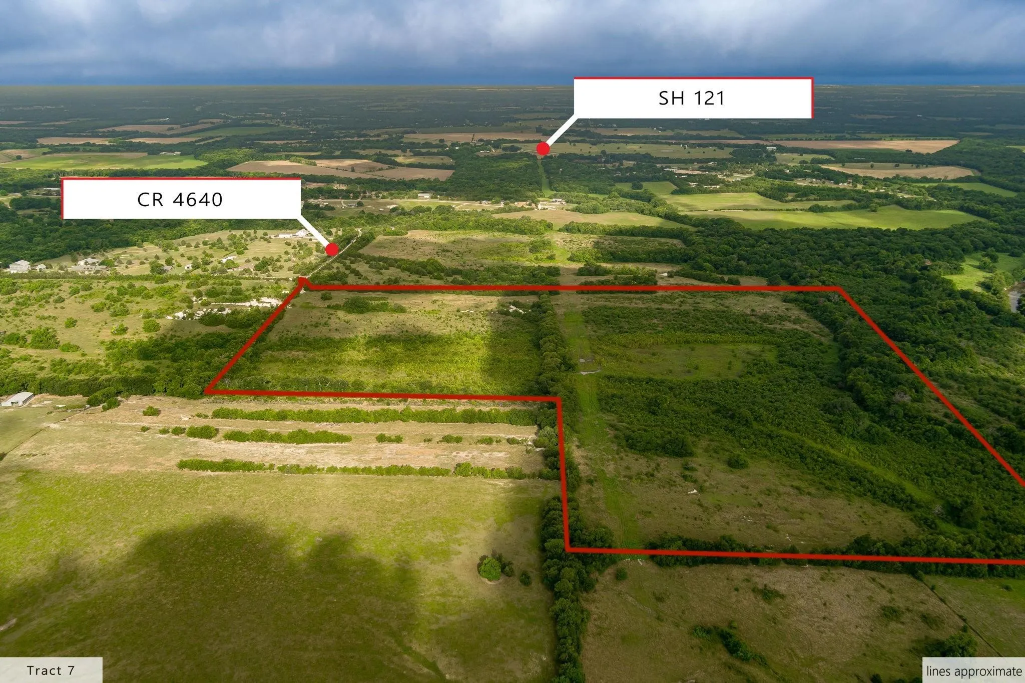 Expansive aerial landscape highlighting a large tract of land, outlined in red, featuring varied terrain including open fields and wooded areas