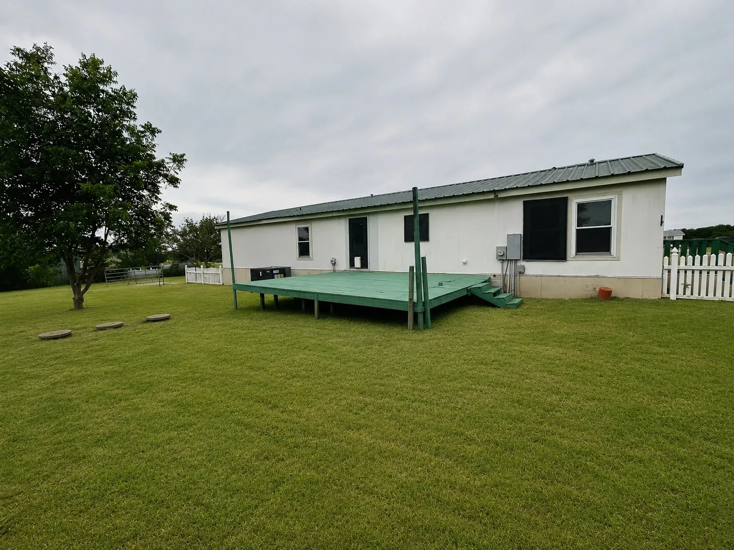 Expansive green lawn featuring a large tree and stepping stones