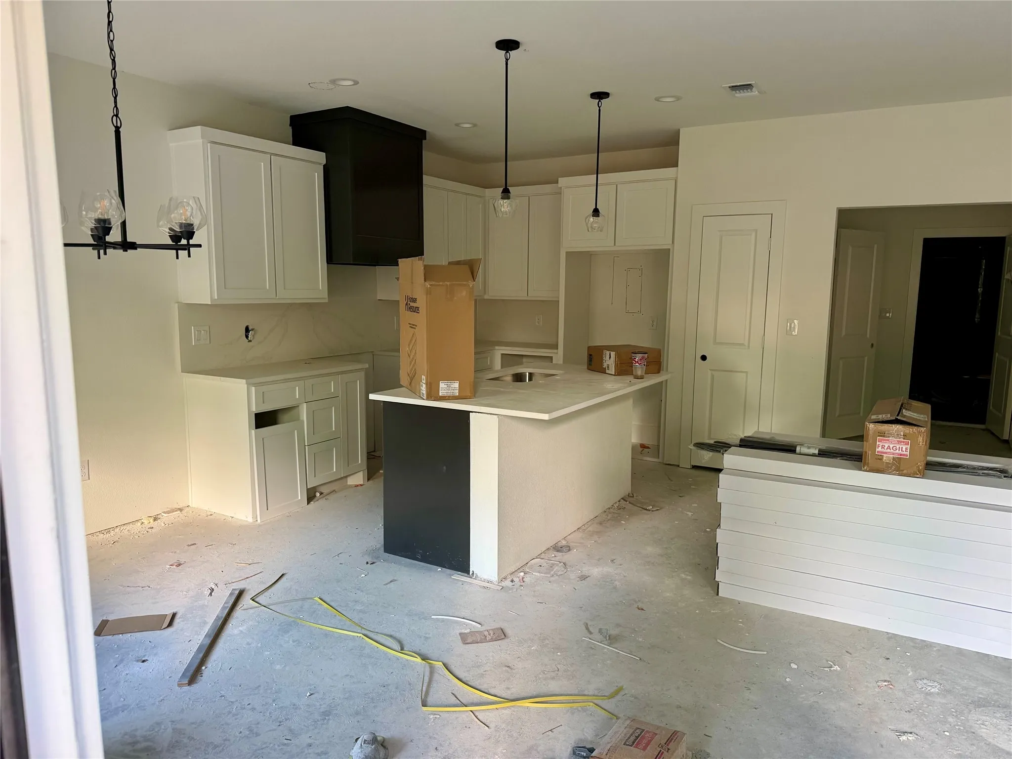 Kitchen featuring a center island, white cabinetry, a black range hood, and pendant lighting