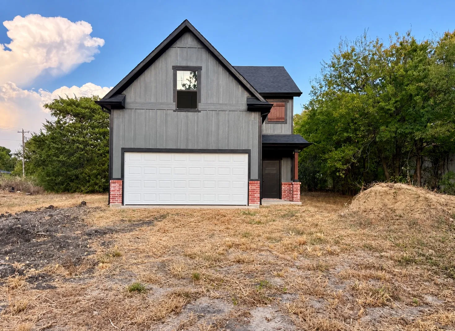 Two-story residence featuring grey vertical siding, a black gable roof, and a two-car garage