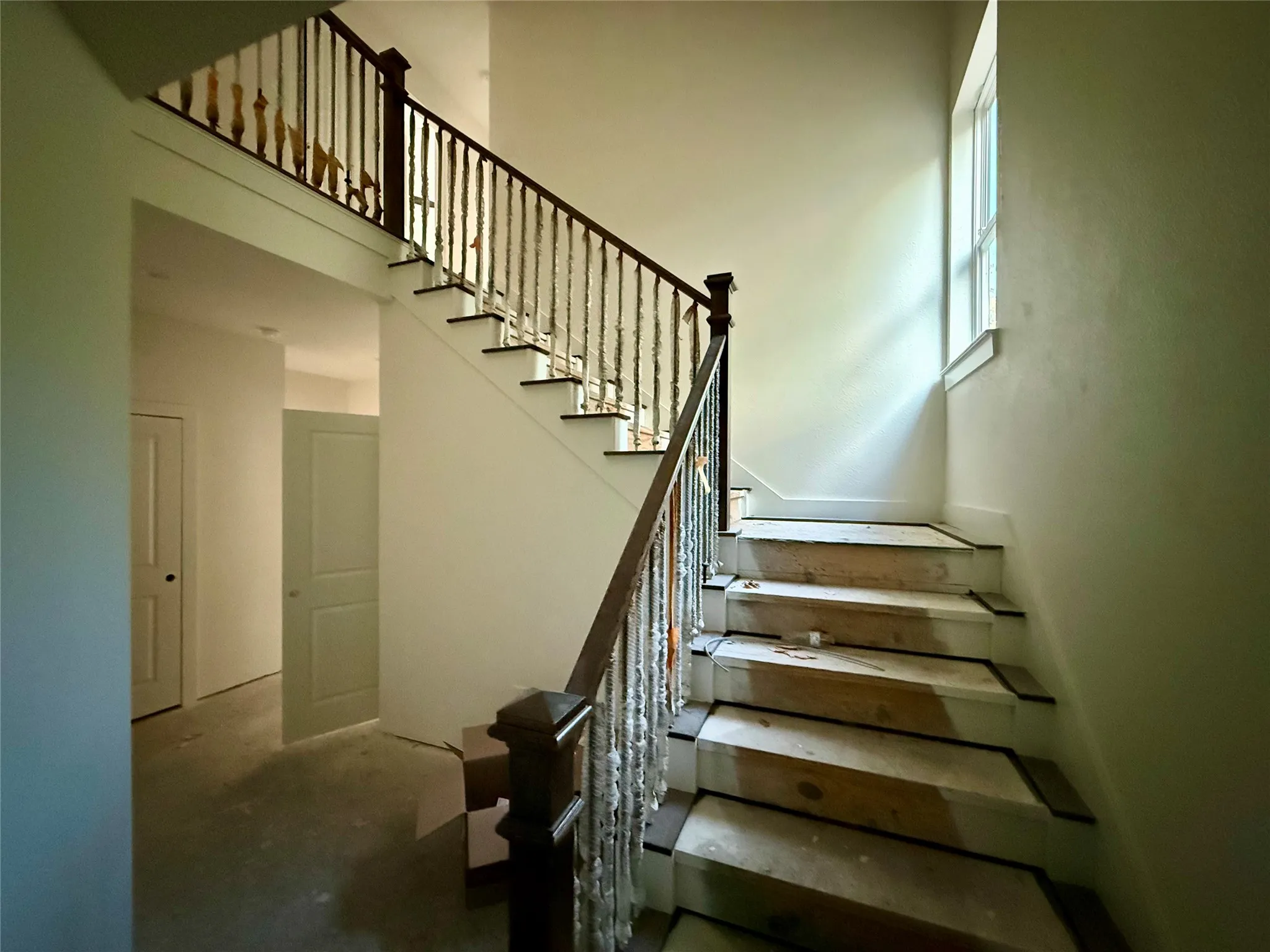 Staircase featuring dark wood handrail, wrought iron balusters, and a window providing natural light