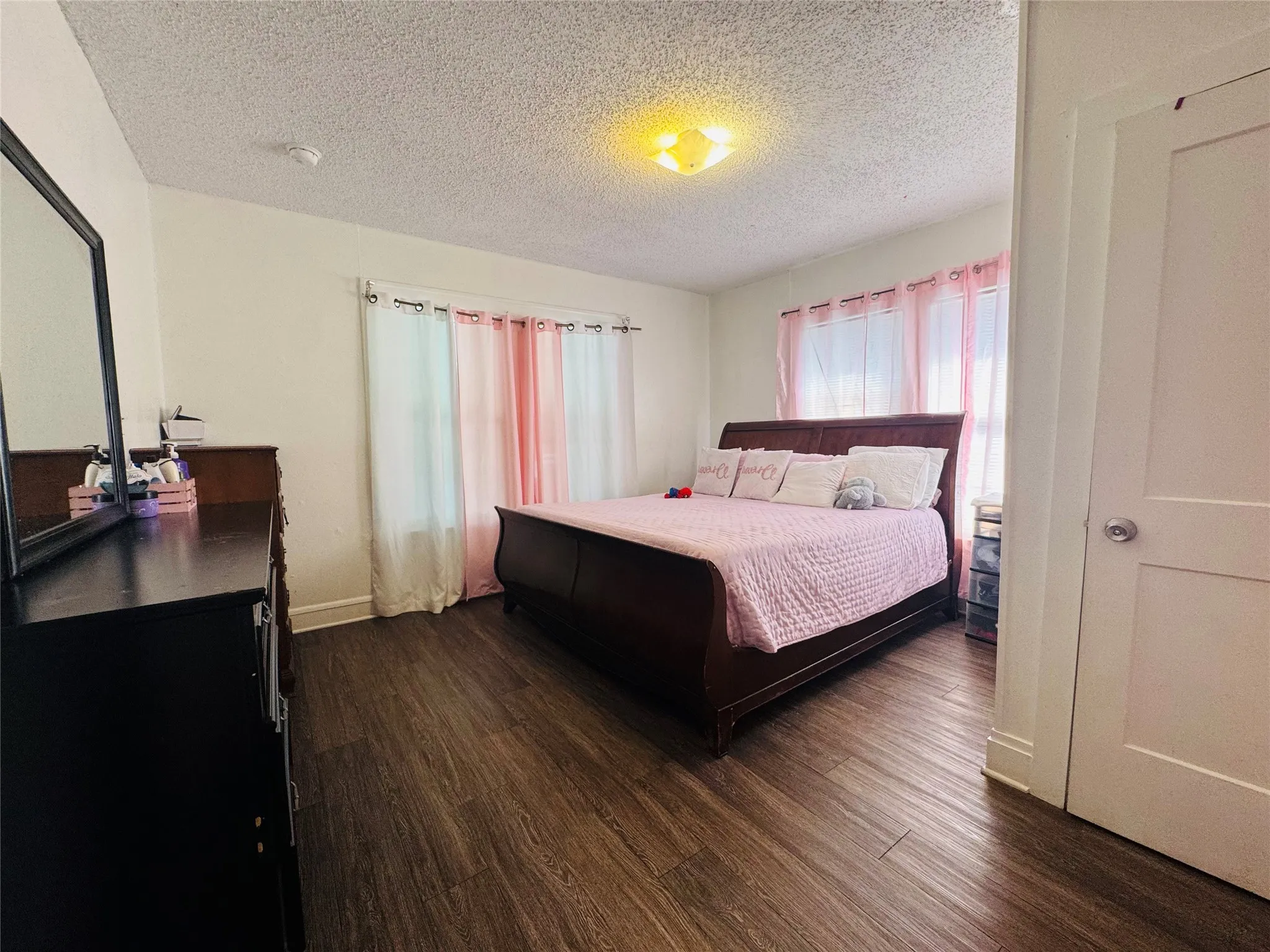 Room featuring wood-finish flooring, white walls, and a white interior door with a silver knob