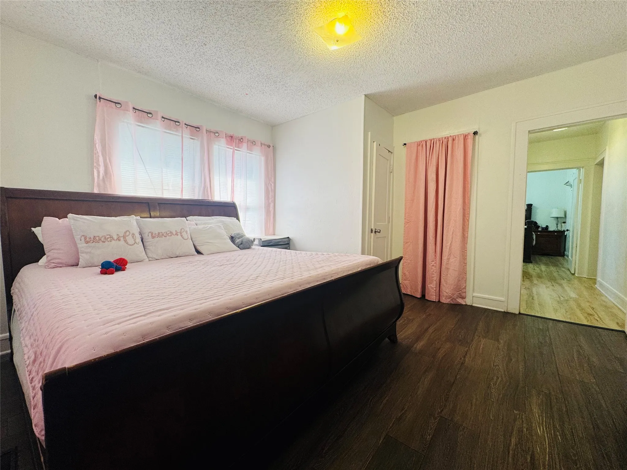 Interior room featuring wood-finish flooring, white painted walls, and a textured ceiling