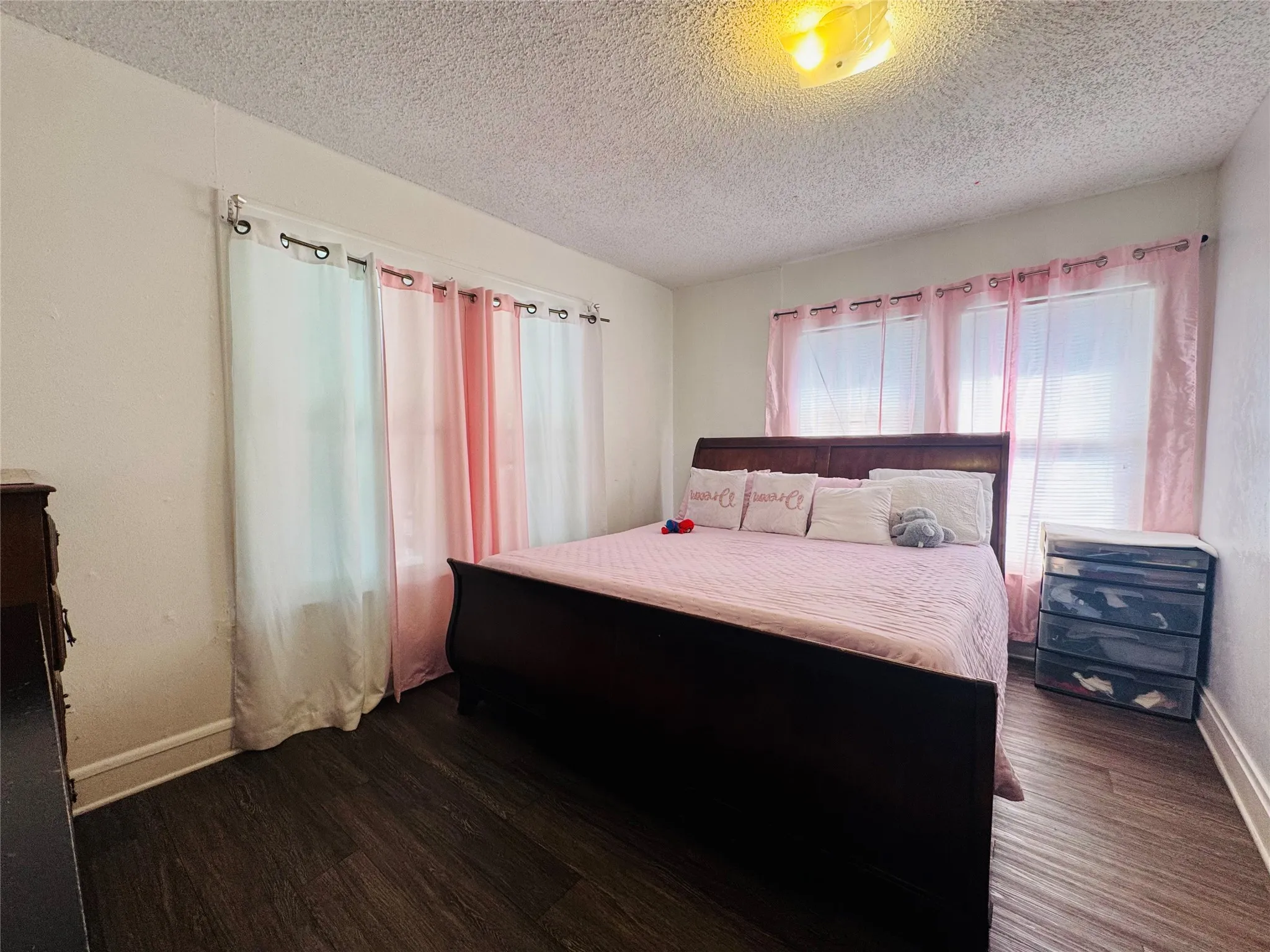 Bedroom featuring dark wood-finish flooring, white baseboards, and a textured white ceiling