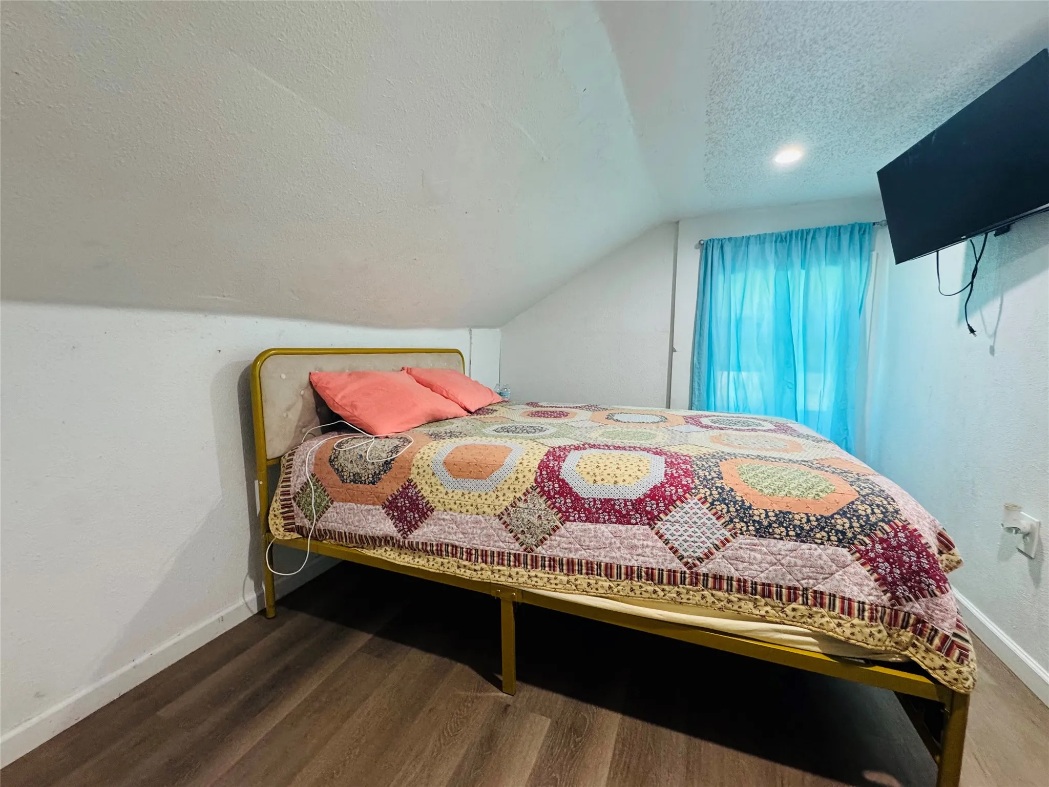 Room featuring wood-finish flooring, a sloped ceiling, and a recessed ceiling light