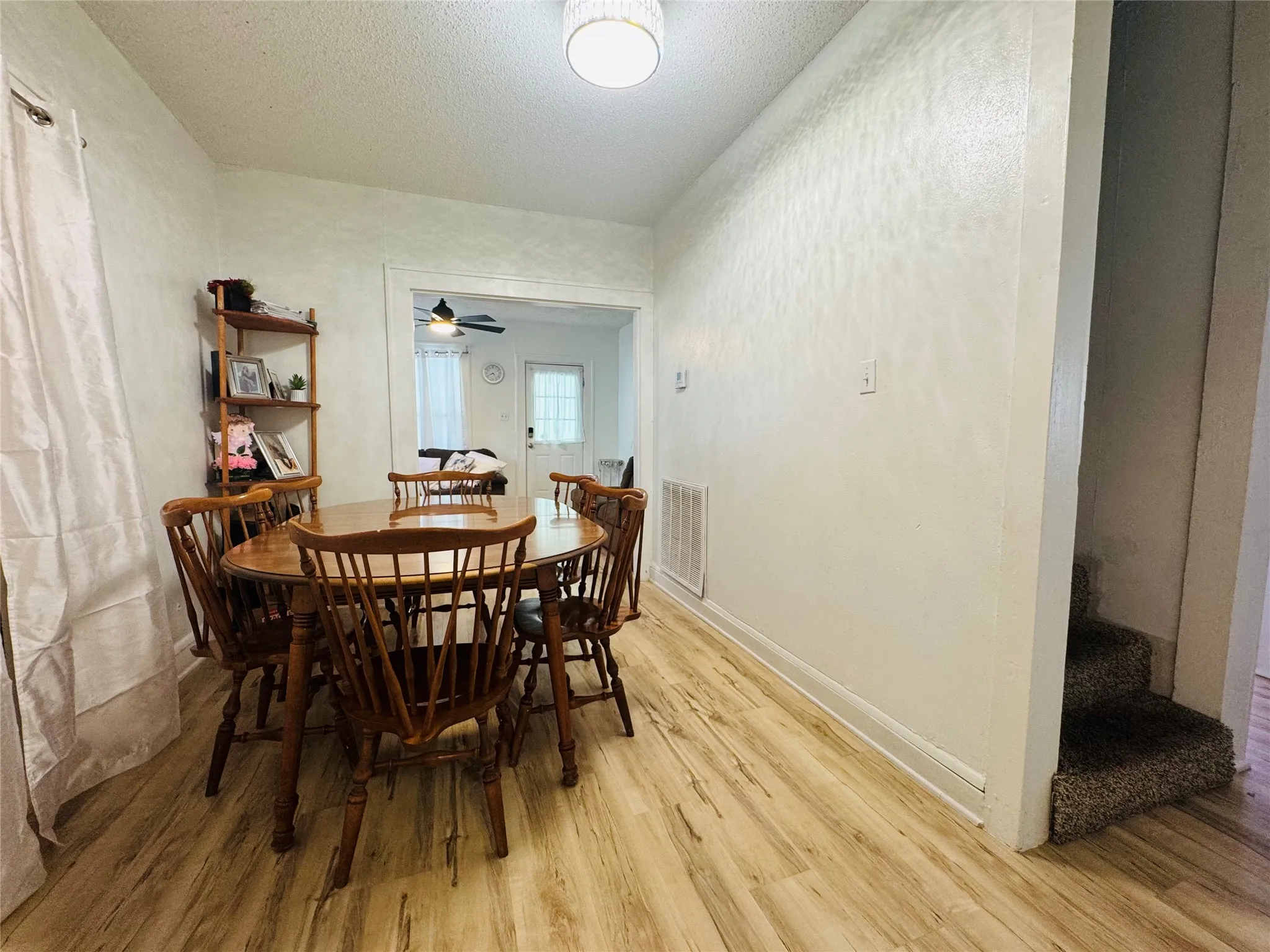 Dining area featuring wood-finish flooring, white painted walls, and an open doorway leading to another room