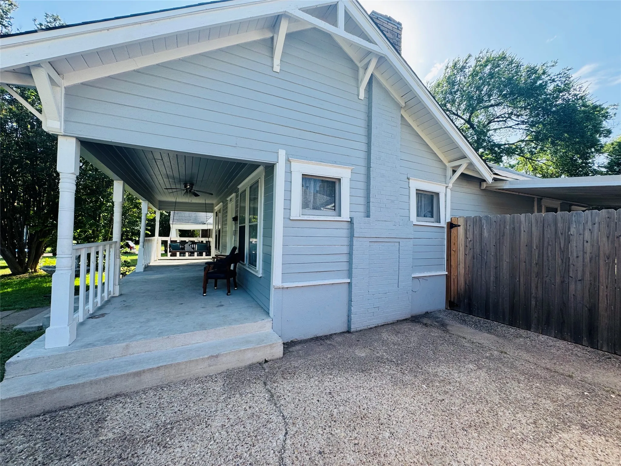 Exterior featuring light blue siding, white trim, and a covered front porch with a ceiling fan