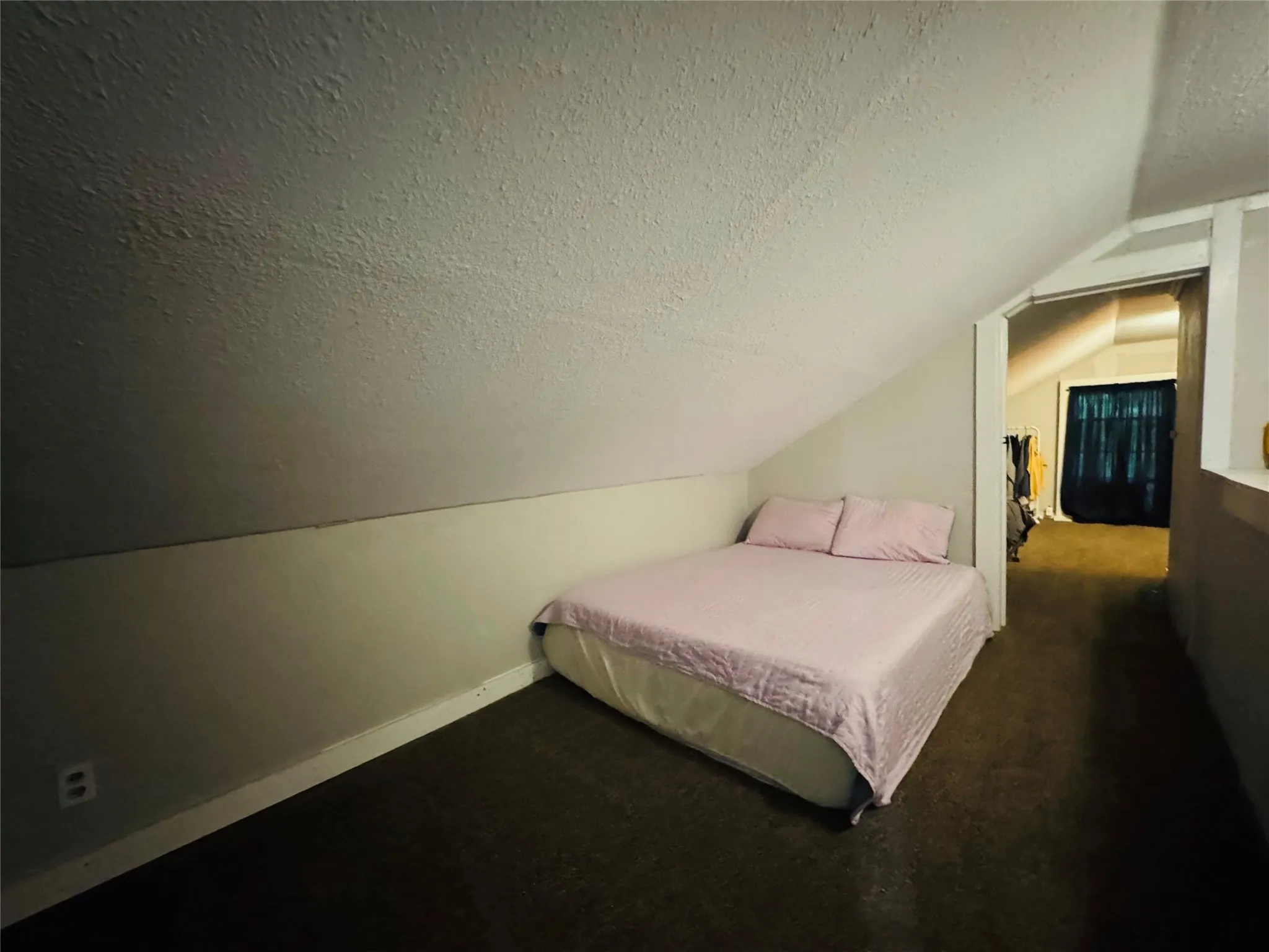 Carpeted room featuring an angled ceiling and a textured finish