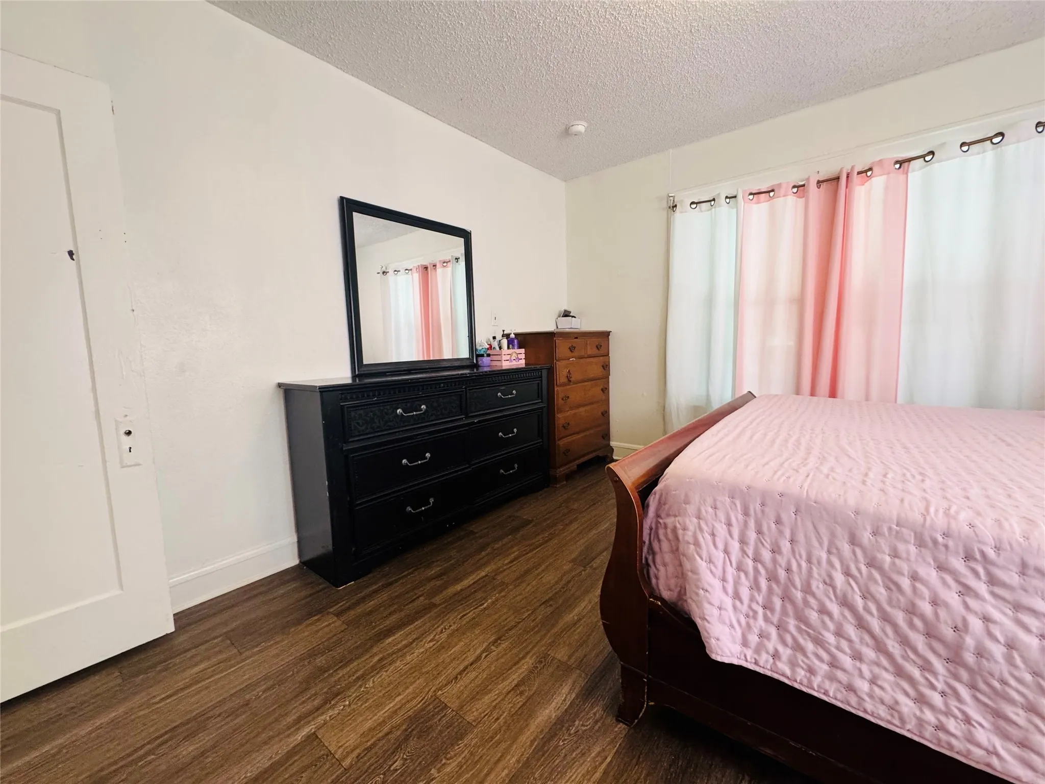 Room featuring wood-finish flooring, white walls, and a white interior door