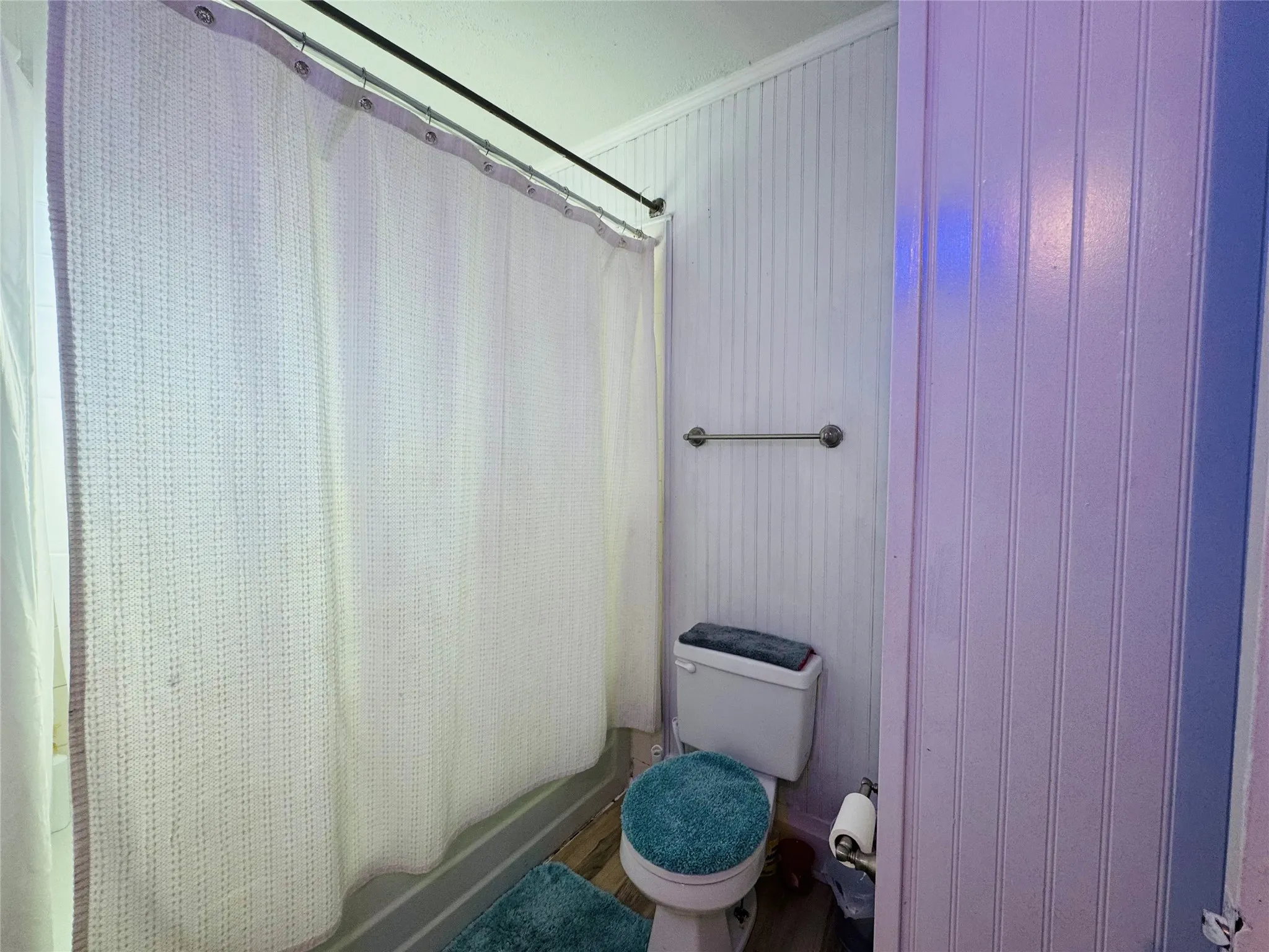 Bathroom featuring beadboard paneling, wood-finish flooring, and a white toilet