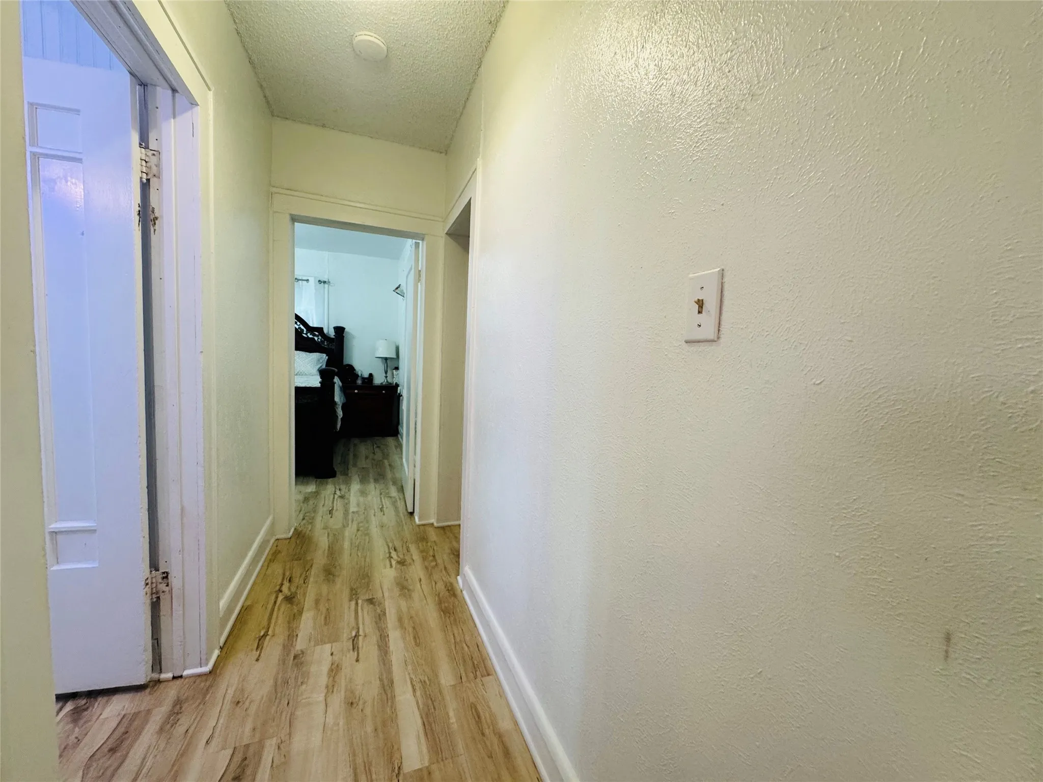 Hallway with wood-finish flooring, white baseboards, and neutral wall tones