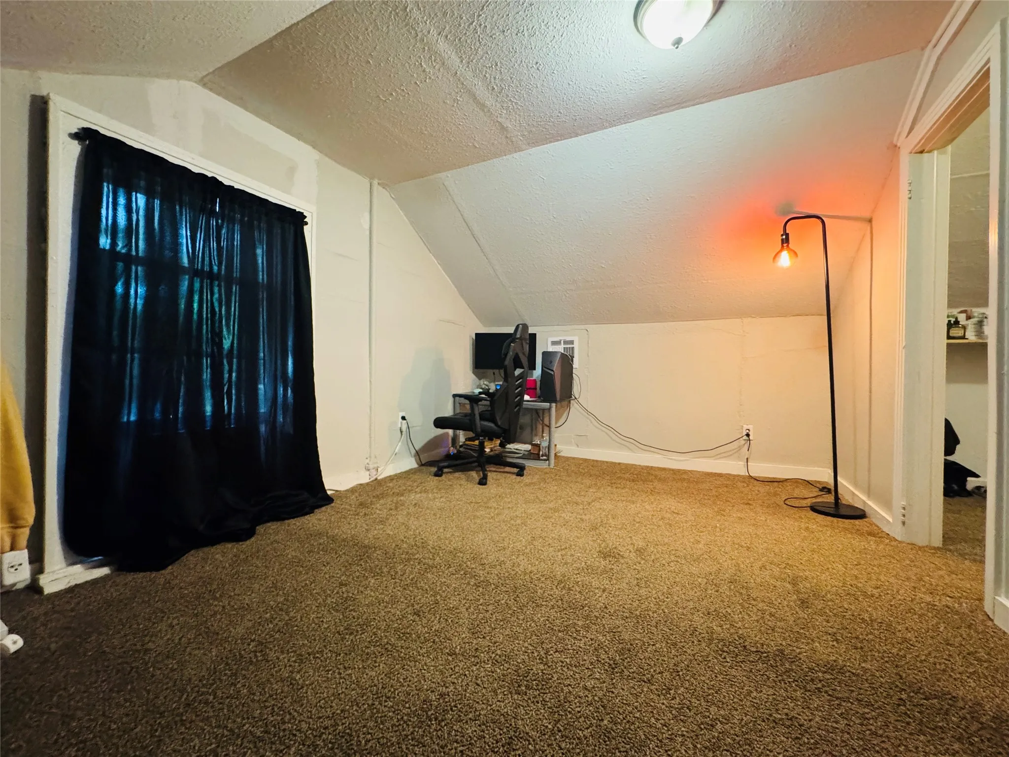 Carpeted room featuring a window with white trim, sloped ceiling, and a flush mount ceiling light fixture