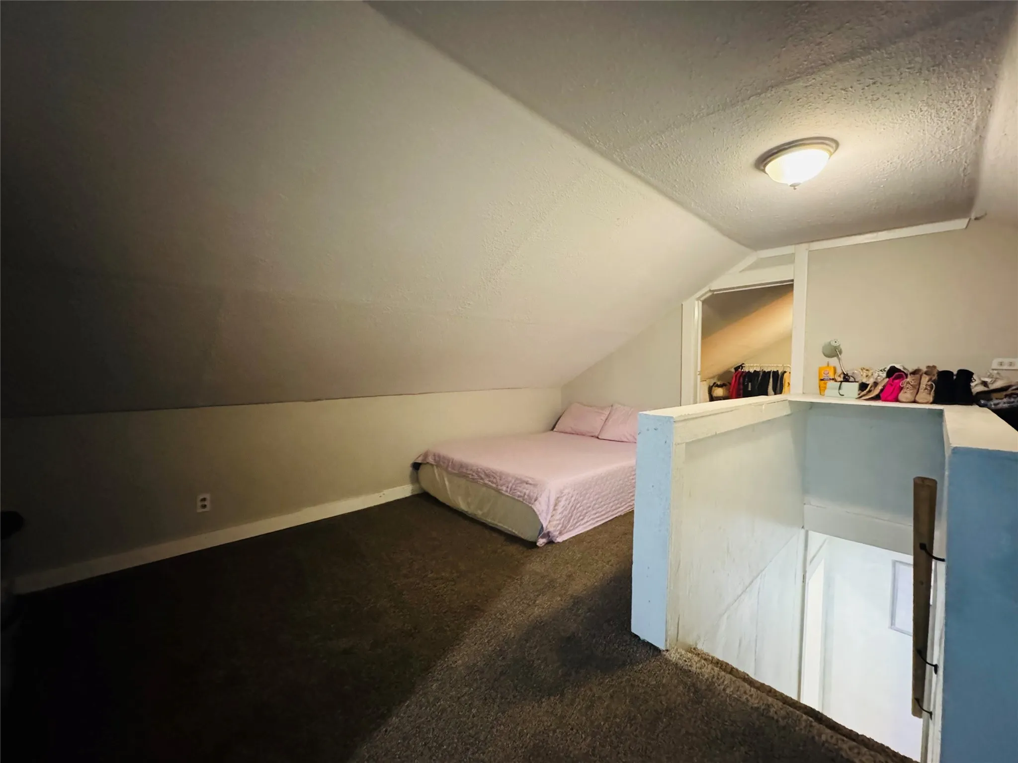 Carpeted attic space featuring sloped ceilings, a semi-flush mount ceiling light, and a partial wall separating the landing