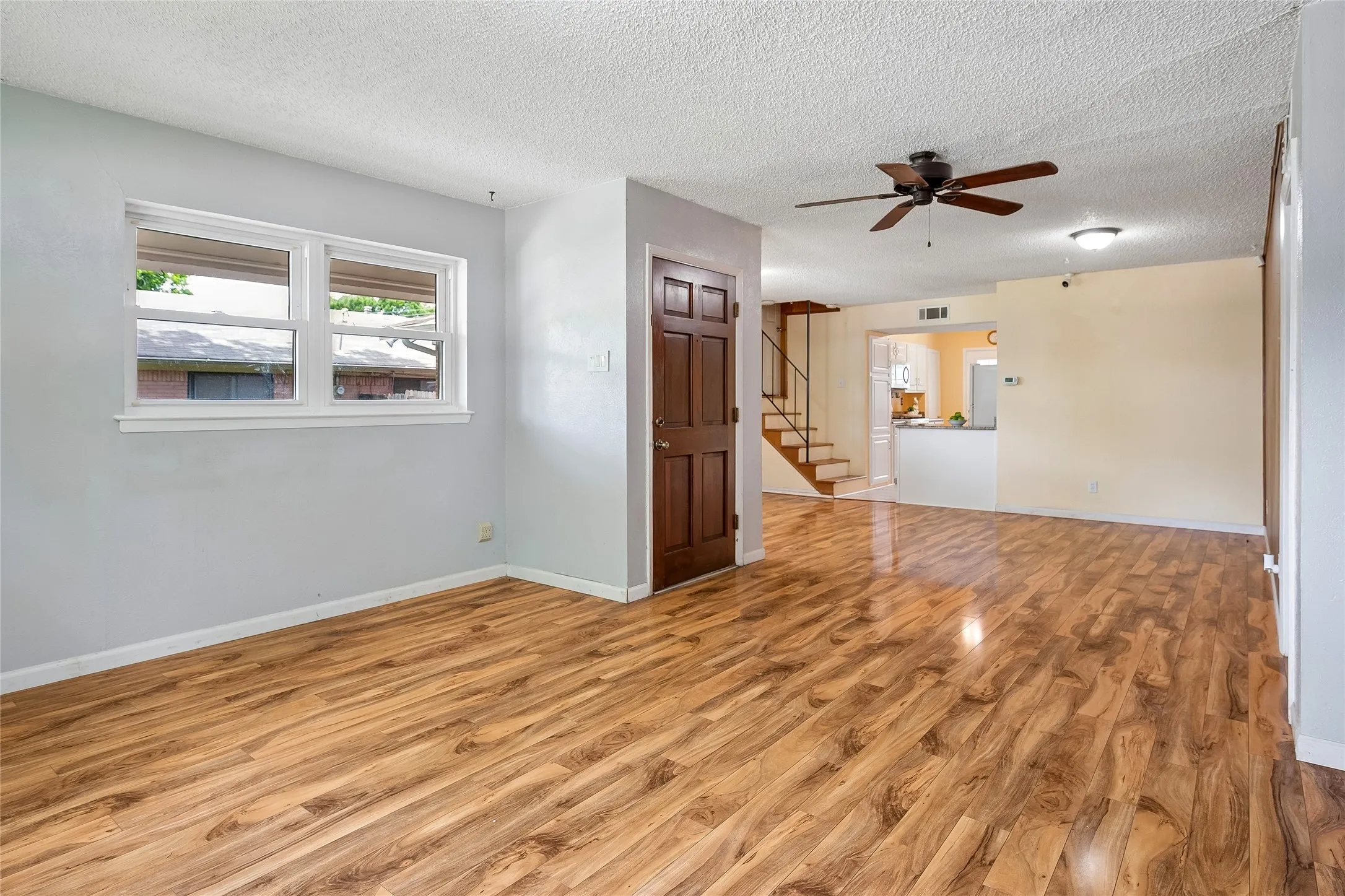 Open living and dining areas with rich wide plank wood-look flooring.