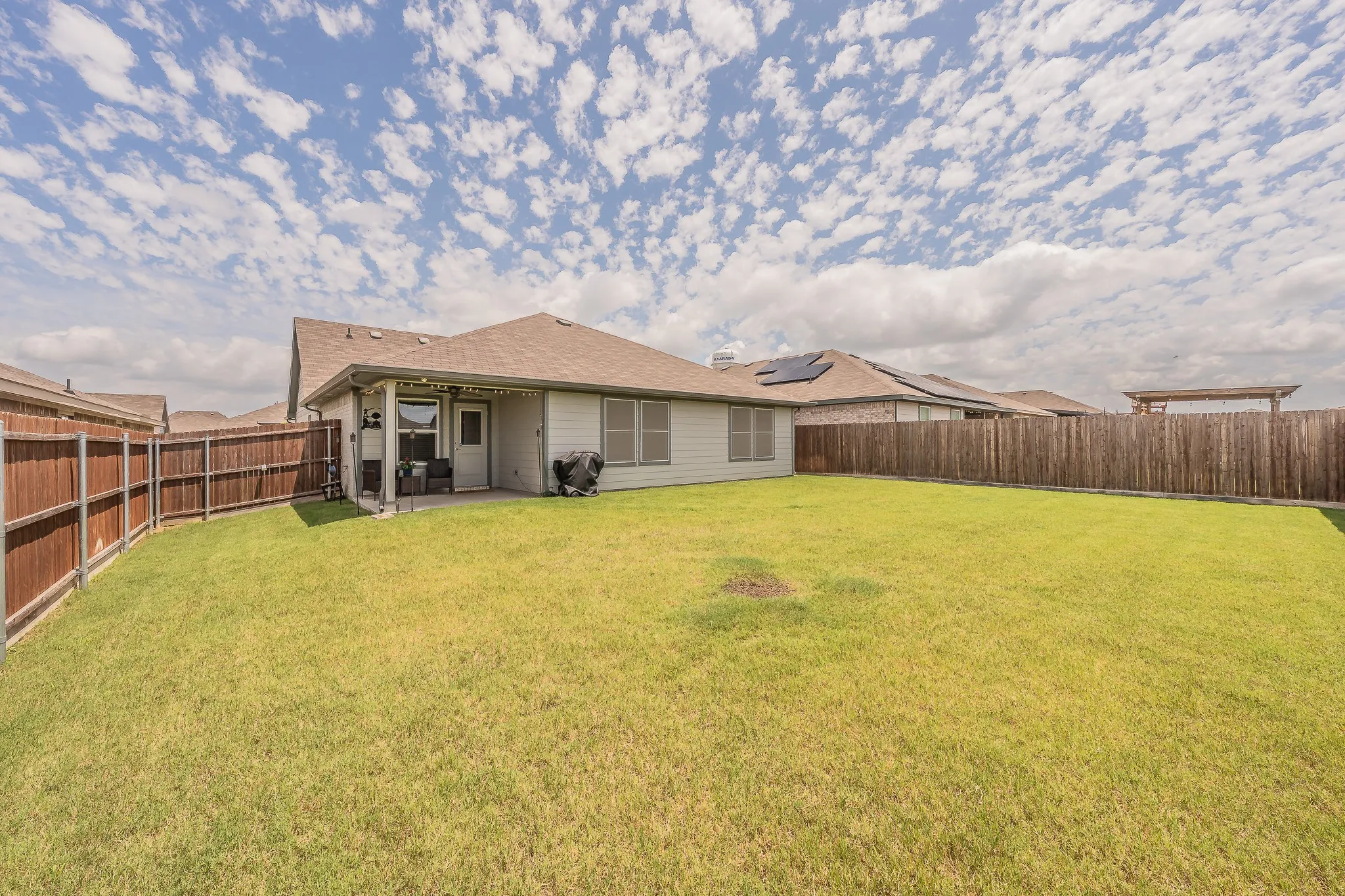 Expansive backyard featuring a manicured lawn, a covered patio, and privacy fencing