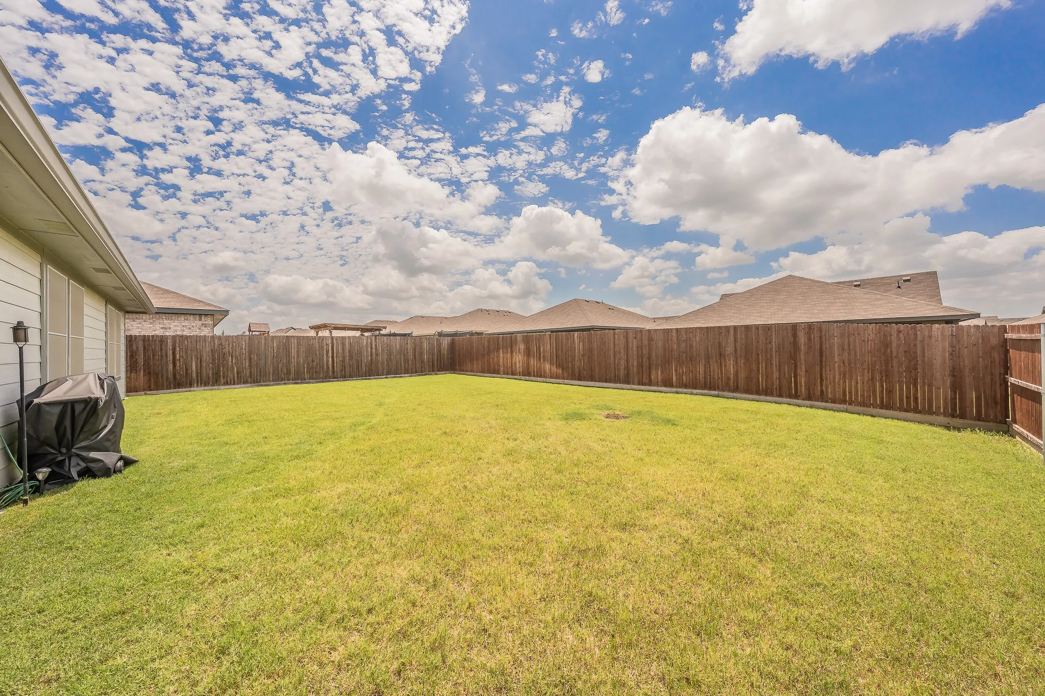 Expansive backyard featuring a manicured lawn, full wood privacy fencing,