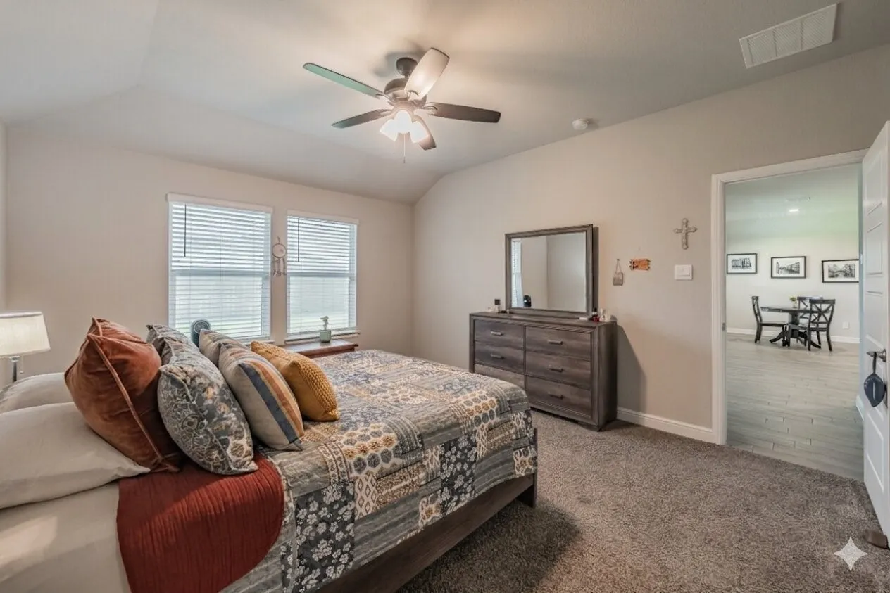 Primary bedroom featurig vaulted ceiling and a ceiling fan