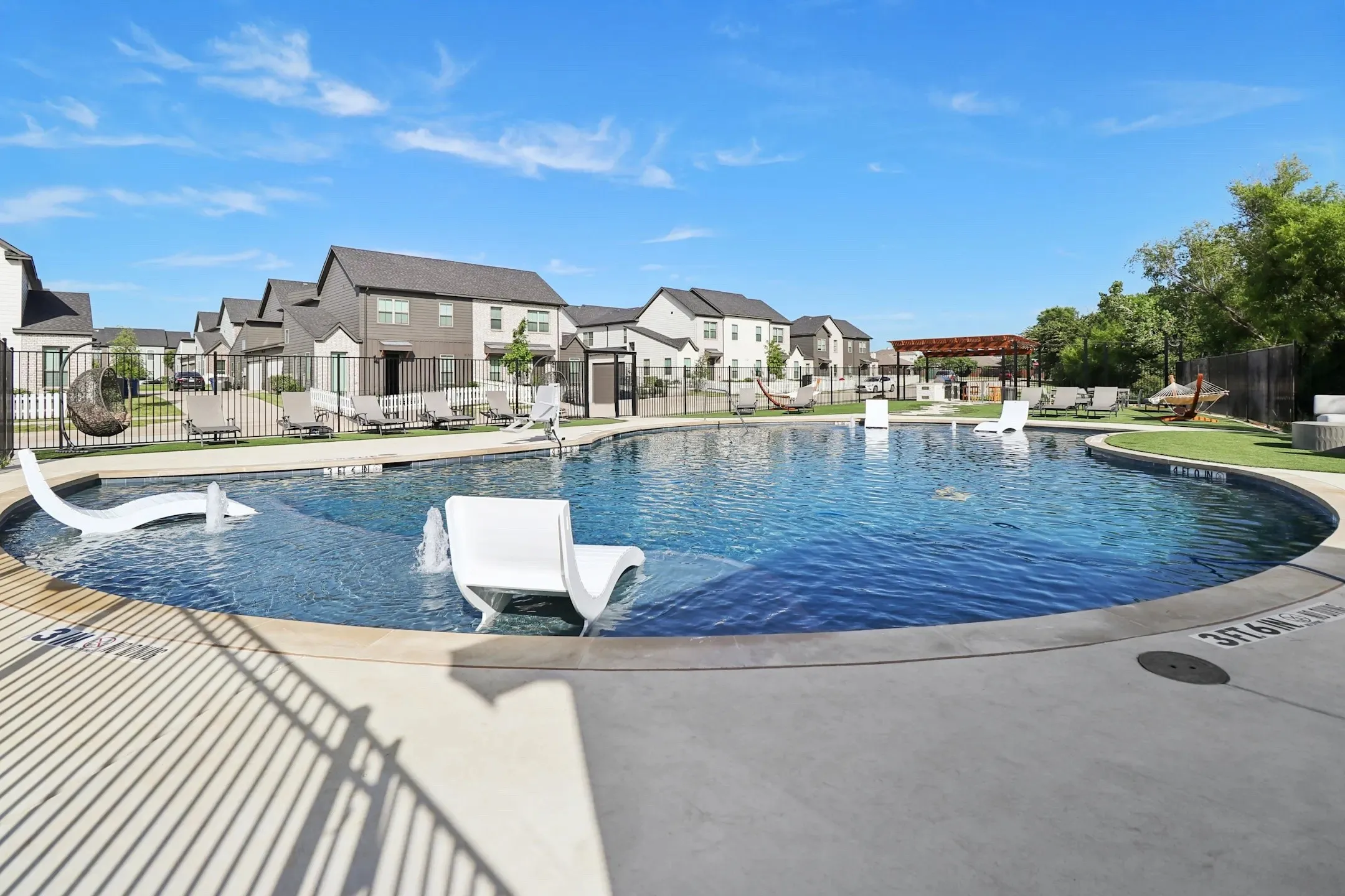 Expansive resort-style swimming pool featuring in-pool loungers and water features