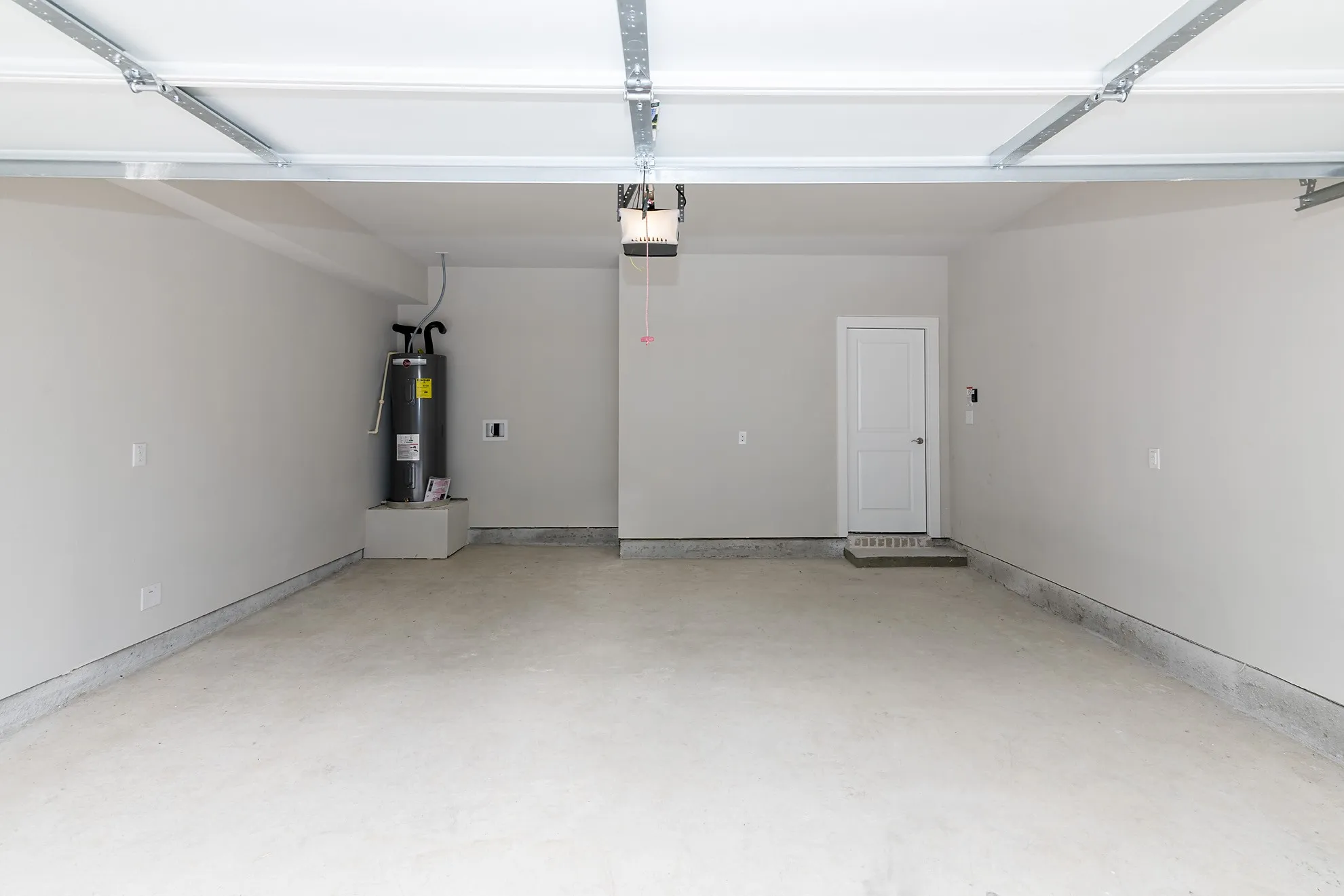 Spacious garage featuring a concrete floor, painted walls, and an overhead garage door mechanism
