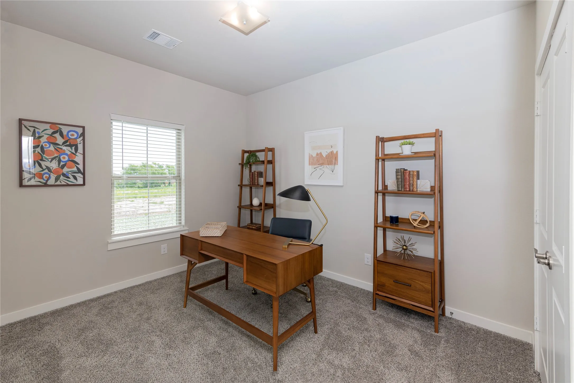 Bright interior room with plush grey carpet, neutral wall paint, and a single window with horizontal blinds