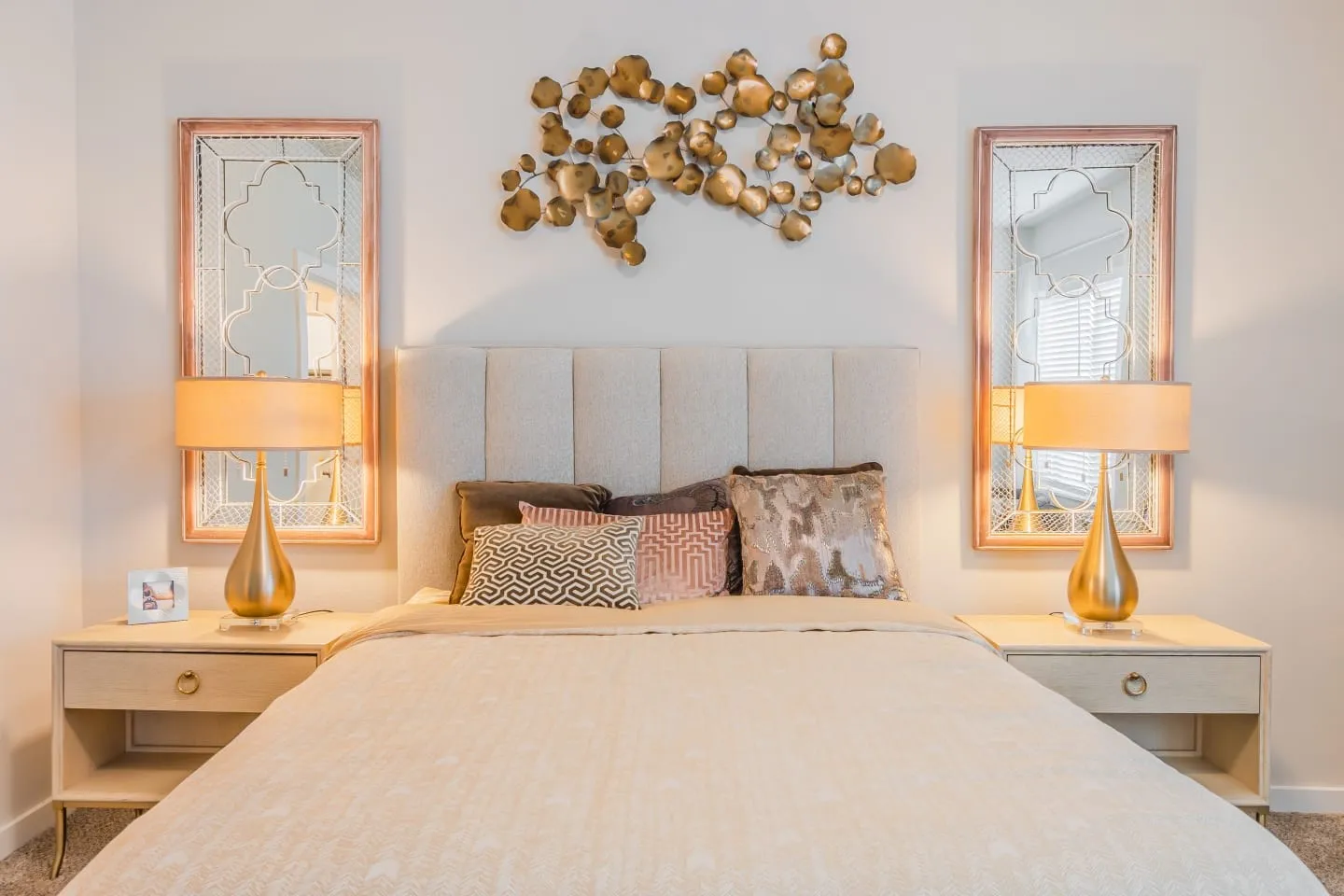Plush upholstered headboard with symmetrical wall mirrors and decorative metal wall art