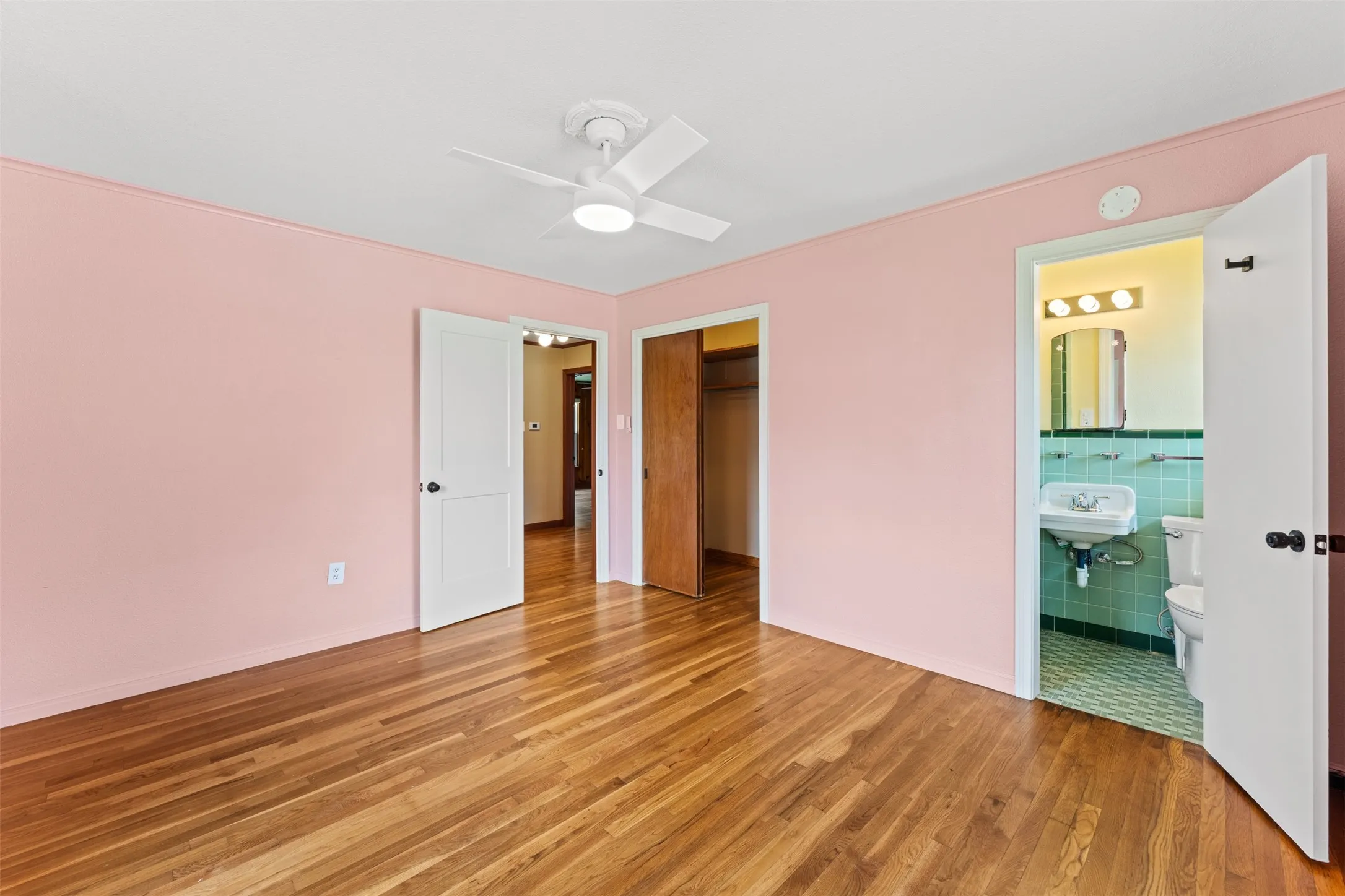 Room with hardwood flooring, a ceiling fan, and a light pink wall color