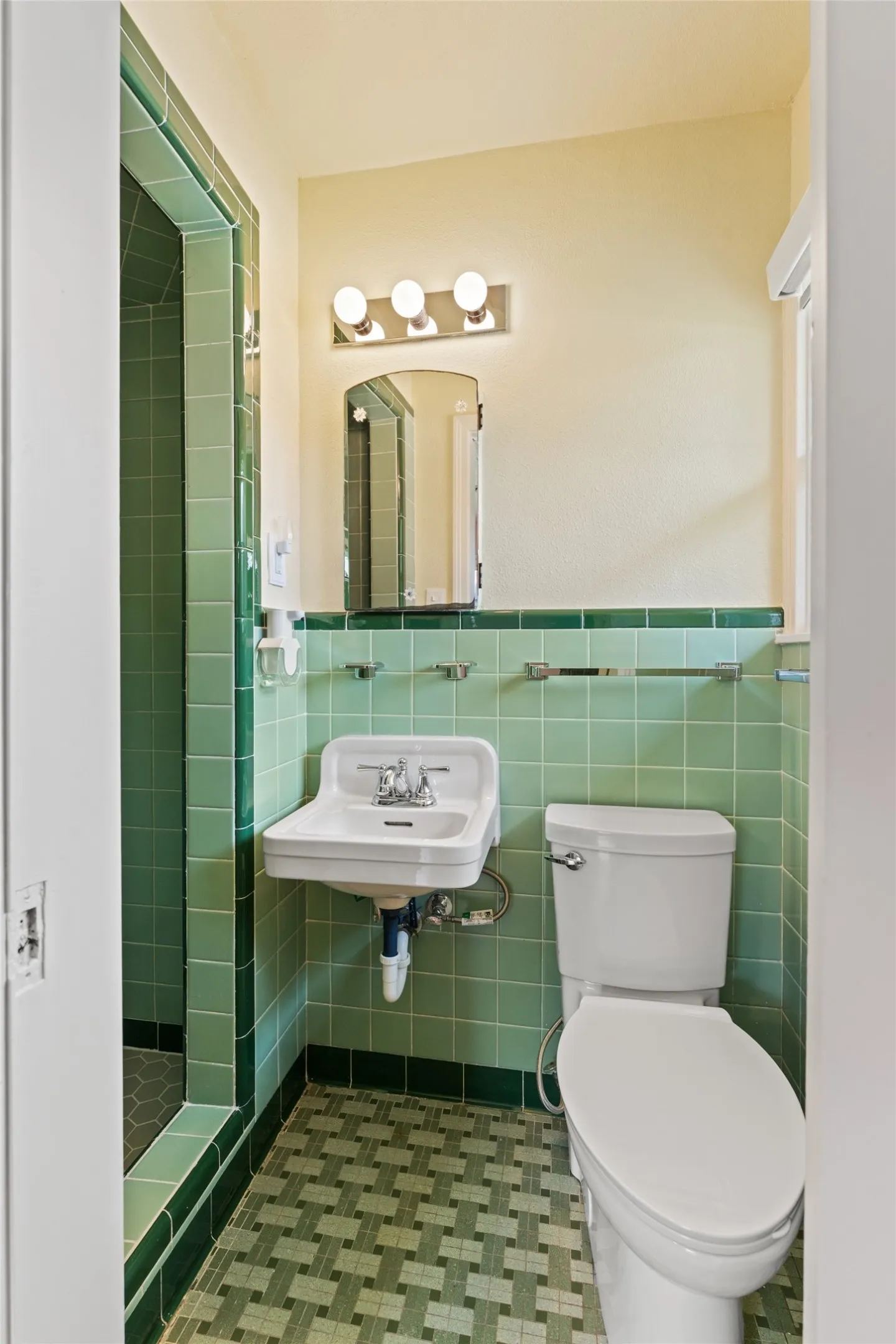 Bathroom featuring a wall-mounted sink, toilet, and a tiled shower enclosure