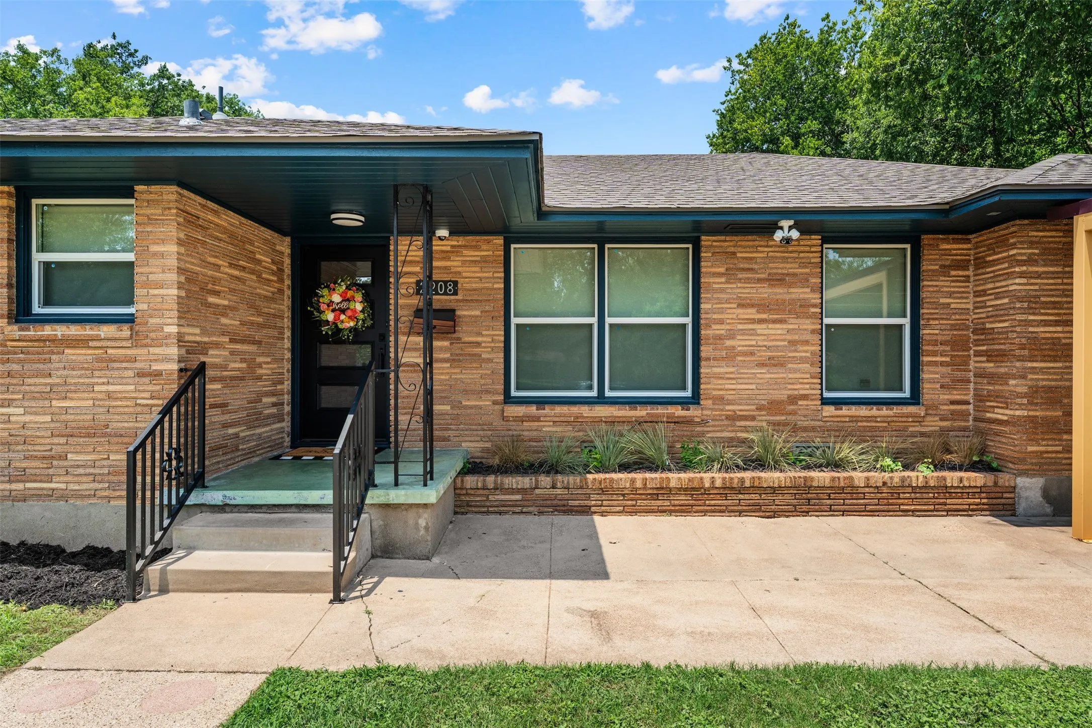 Brick exterior with a covered entry, dark trim windows, and a built-in planter box