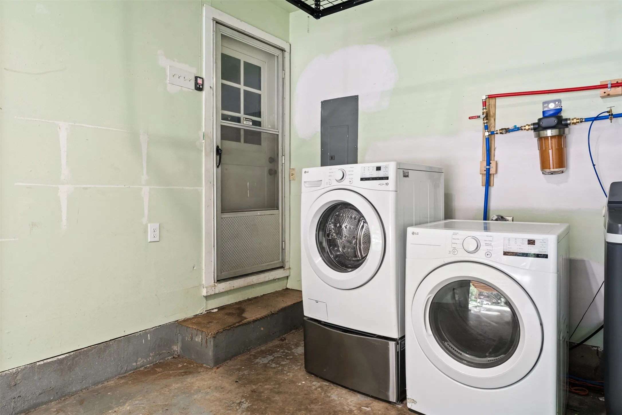 Dedicated utility area featuring a water filtration system and exterior access