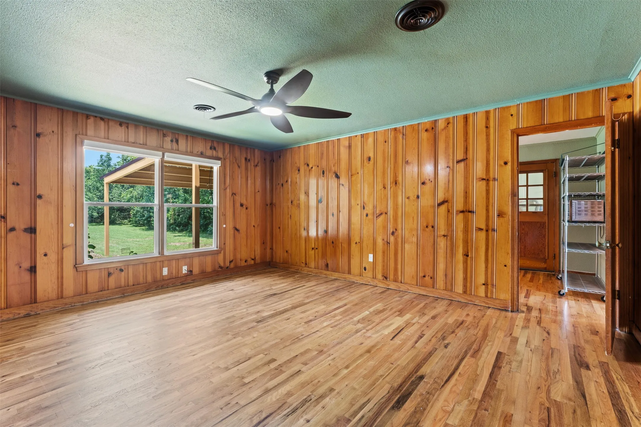 Spacious room featuring wood-finish paneling and coordinating wood-finish flooring