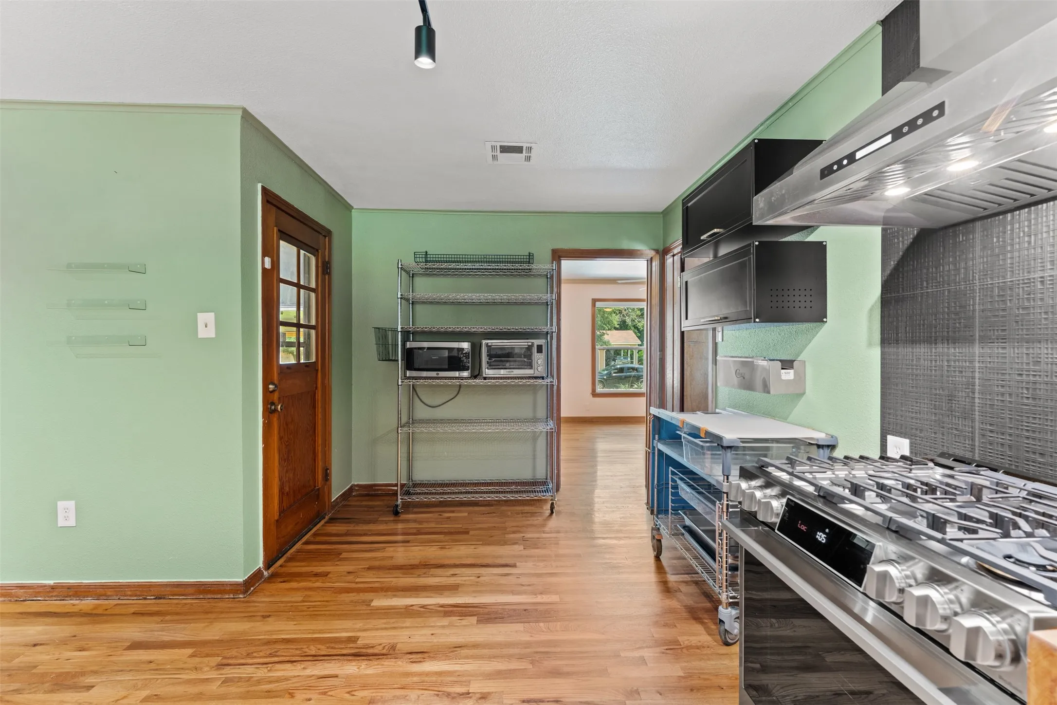 Kitchen area featuring wood-finish flooring and a stainless steel professional-grade range with a substantial ventilation hood