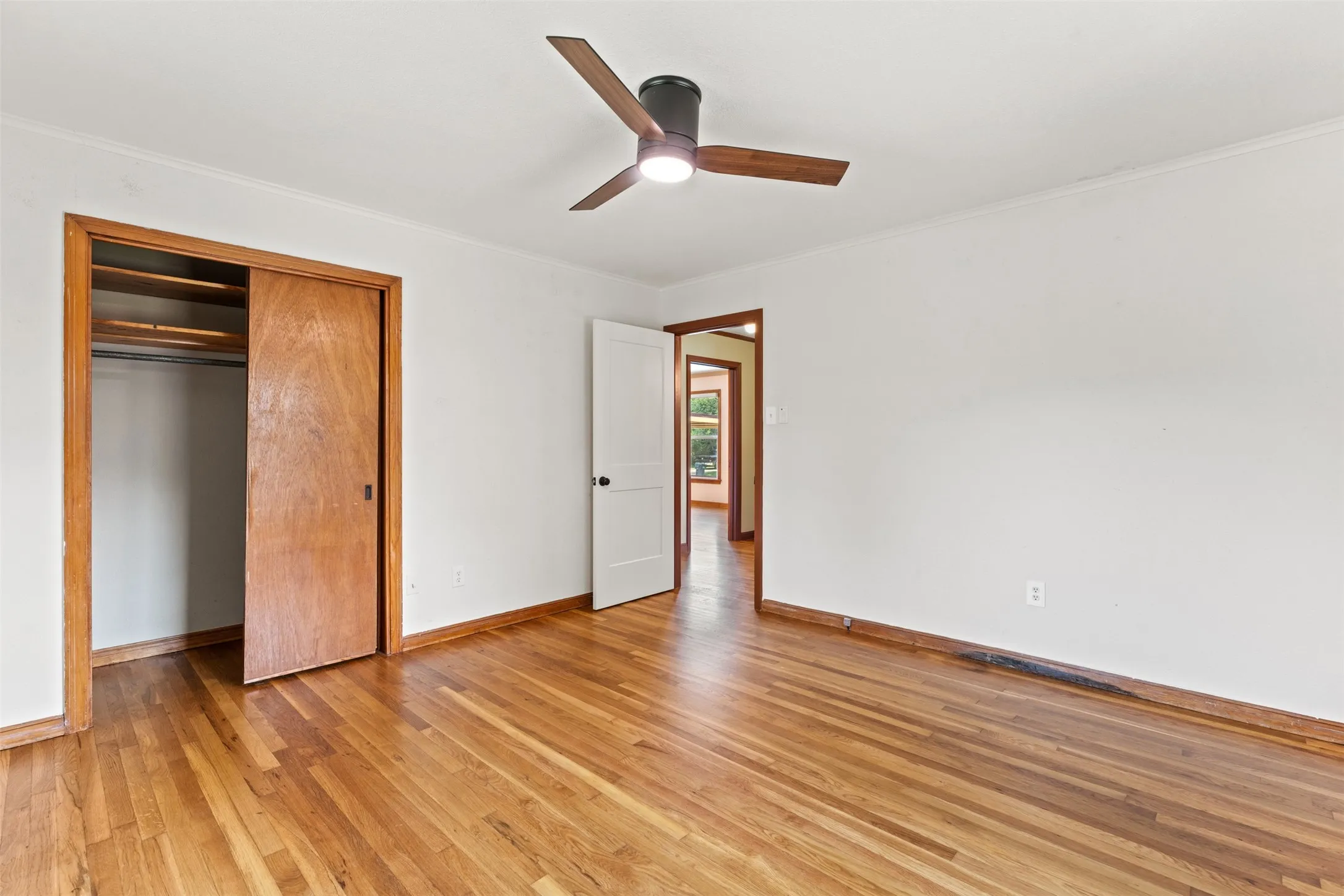 Room featuring wood-finish flooring, white walls, and a ceiling fan