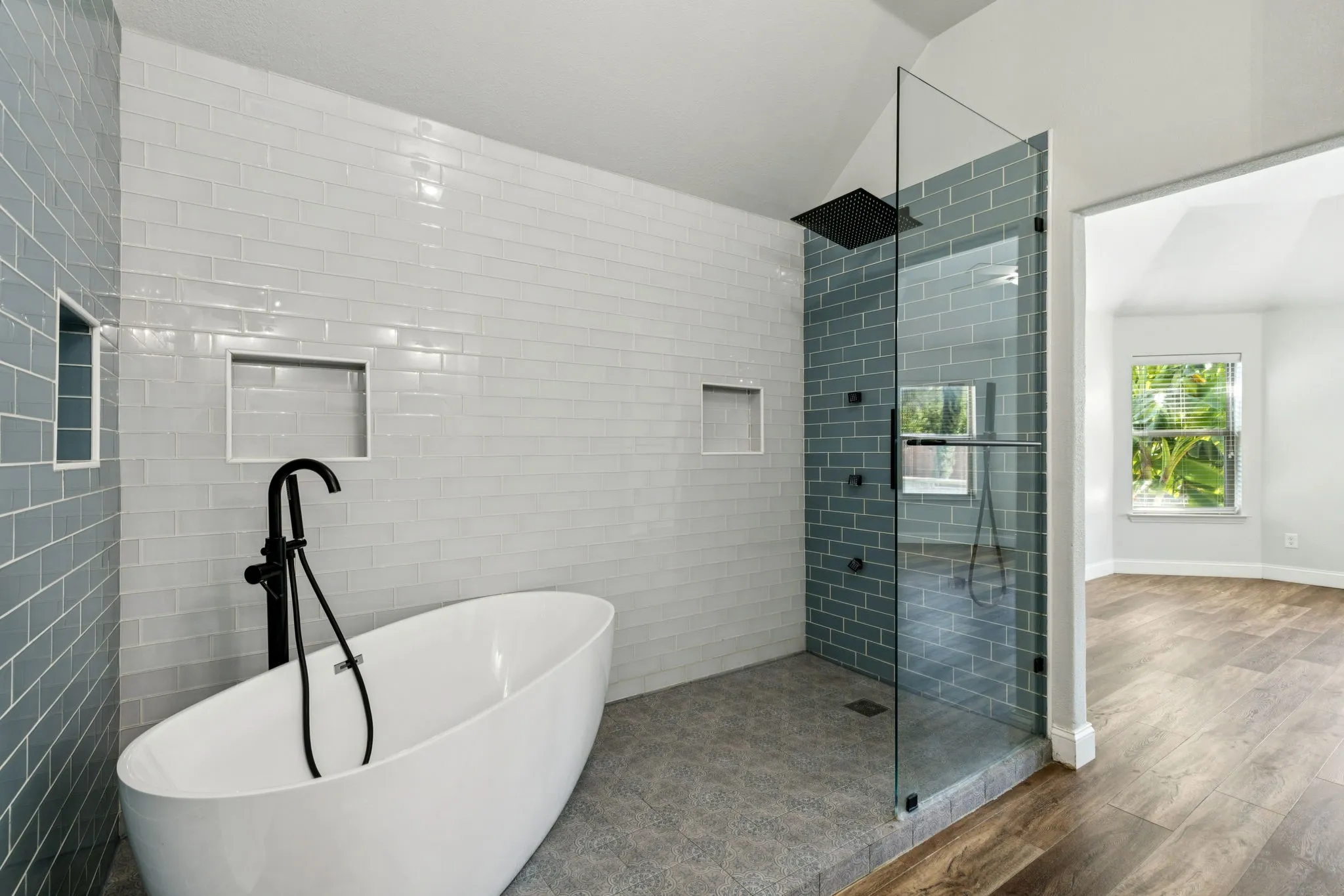 Bathroom with a walk in shower, lofted ceiling, a freestanding tub, wood finished floors, and tile walls