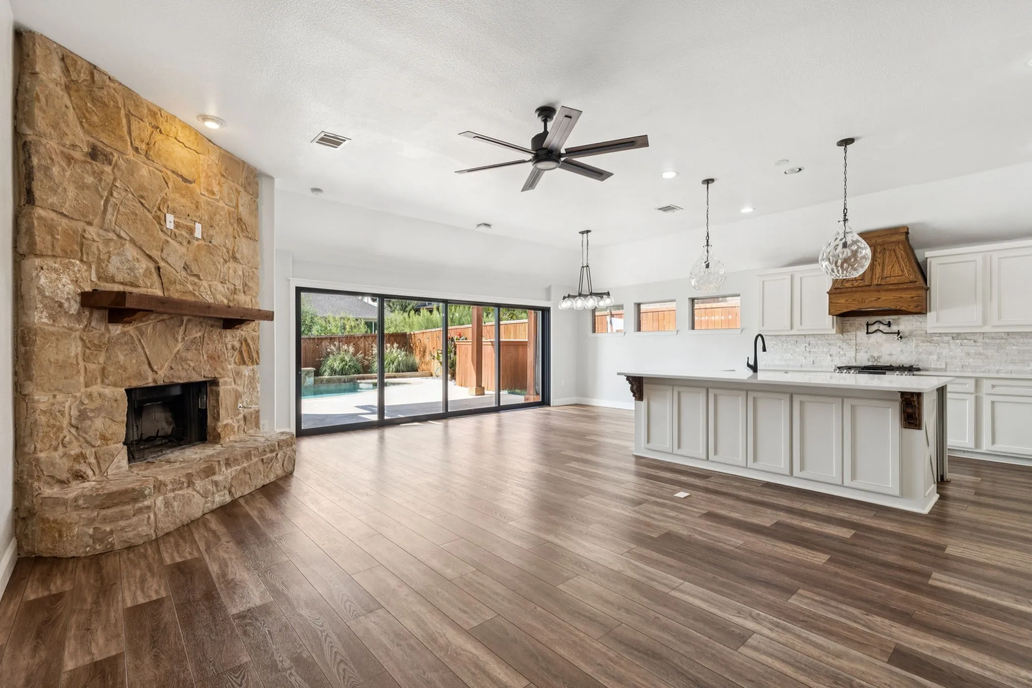 Unfurnished living room with a stone fireplace, ceiling fan, dark wood-type flooring, and recessed lighting