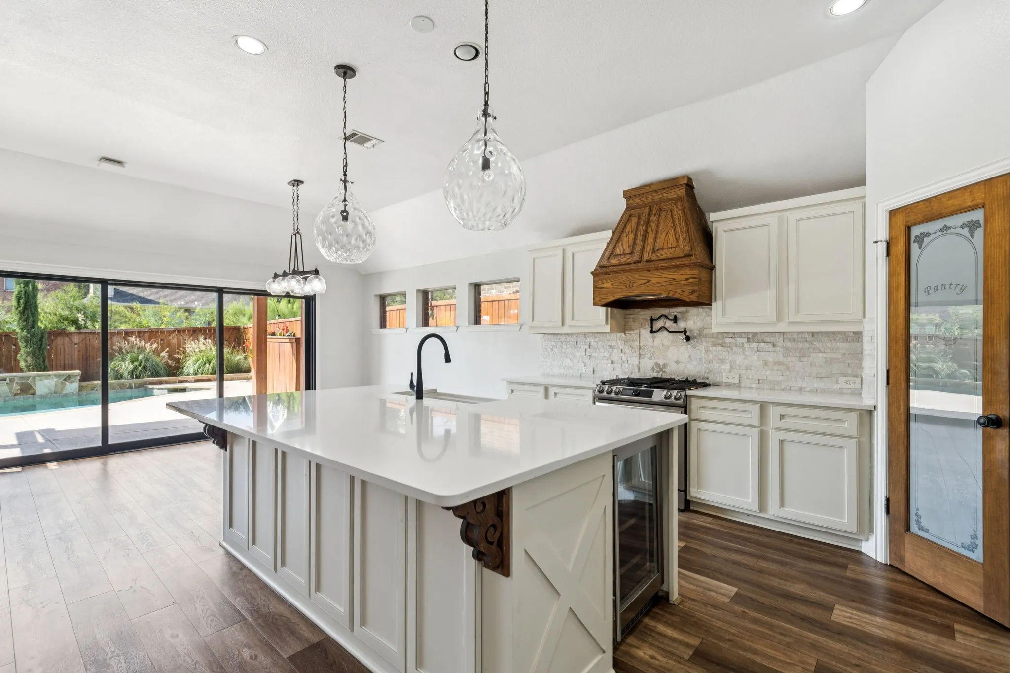 Kitchen with white cabinets, decorative backsplash, recessed lighting, hanging light fixtures, and premium range hood