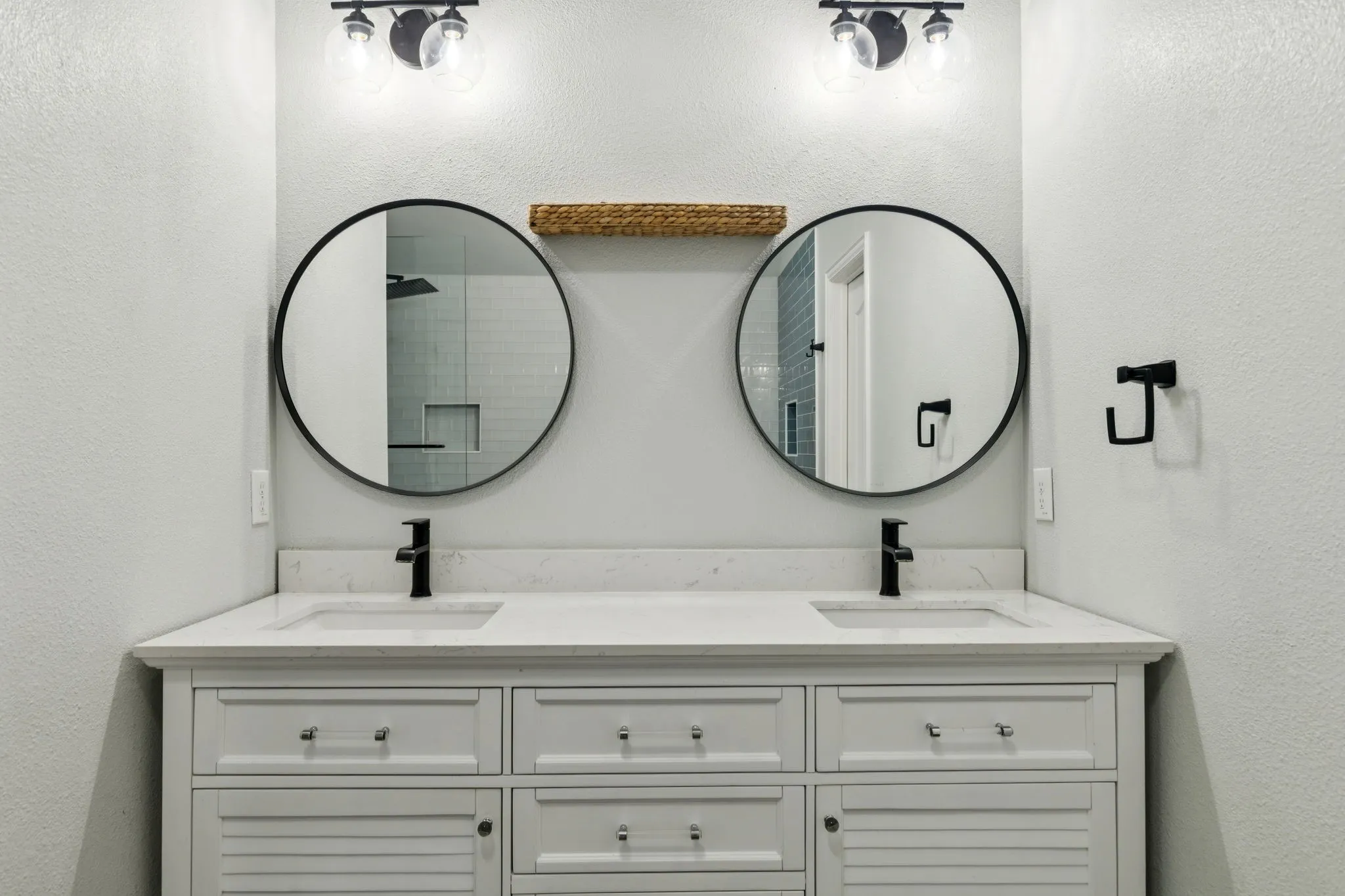 Full bathroom featuring a textured wall, double vanity, and a shower
