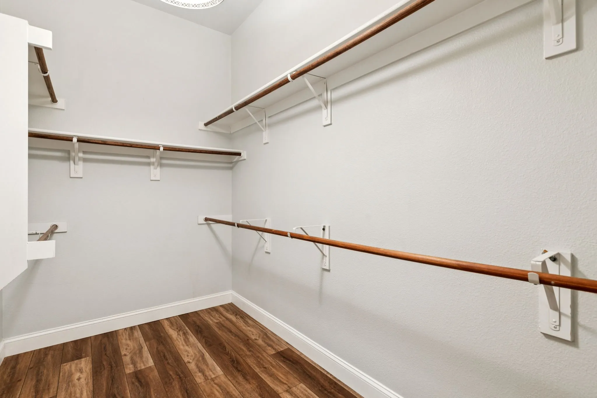 Spacious closet featuring dark wood-style flooring